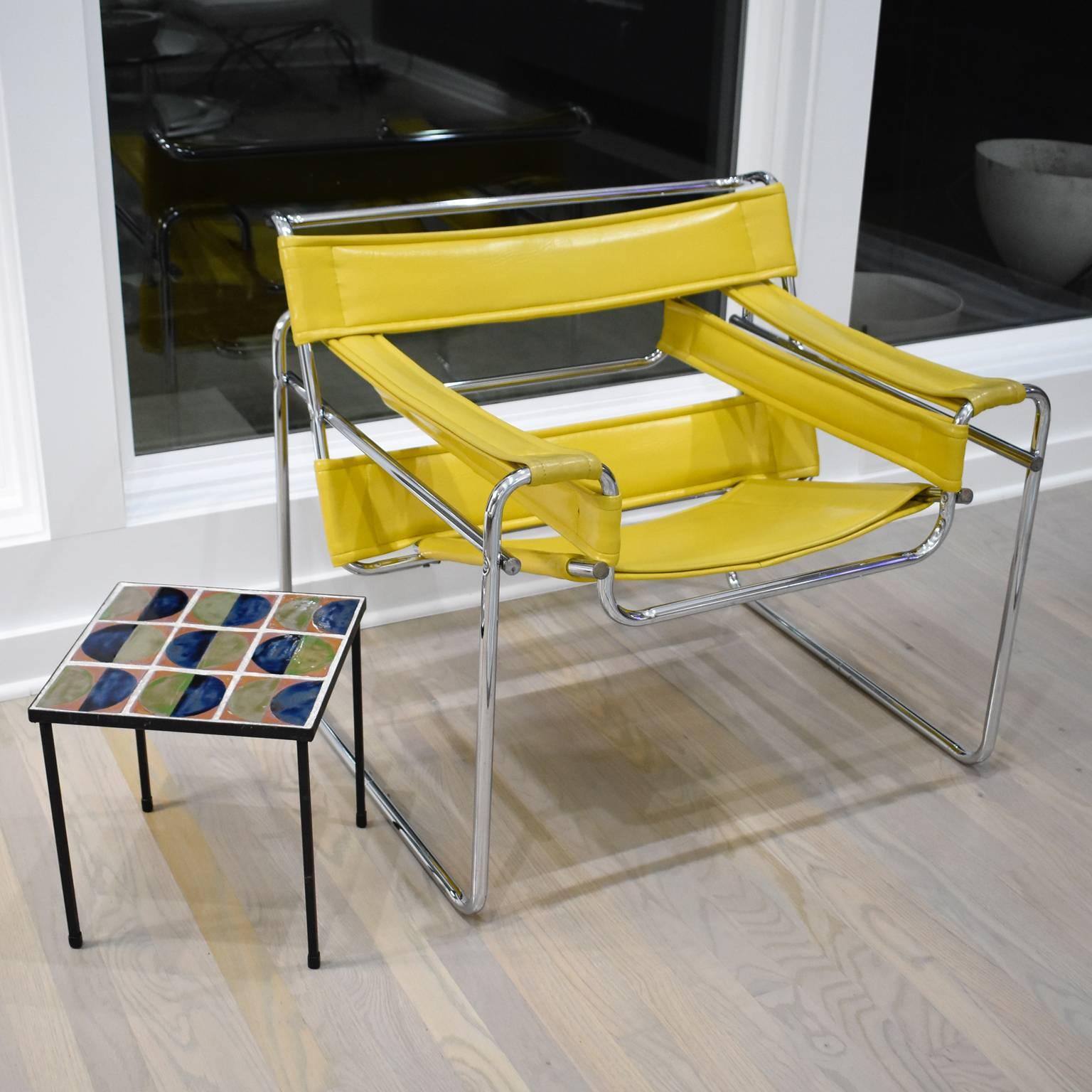 Elegant pair of coffee or side tables reminiscent of the work of the French ceramicist Mado Jolain (1921-). Framing and legs are solid wrought iron with a shiny black finish - simple, functional and sturdy. Lovely colorful glazed ceramic tiles table