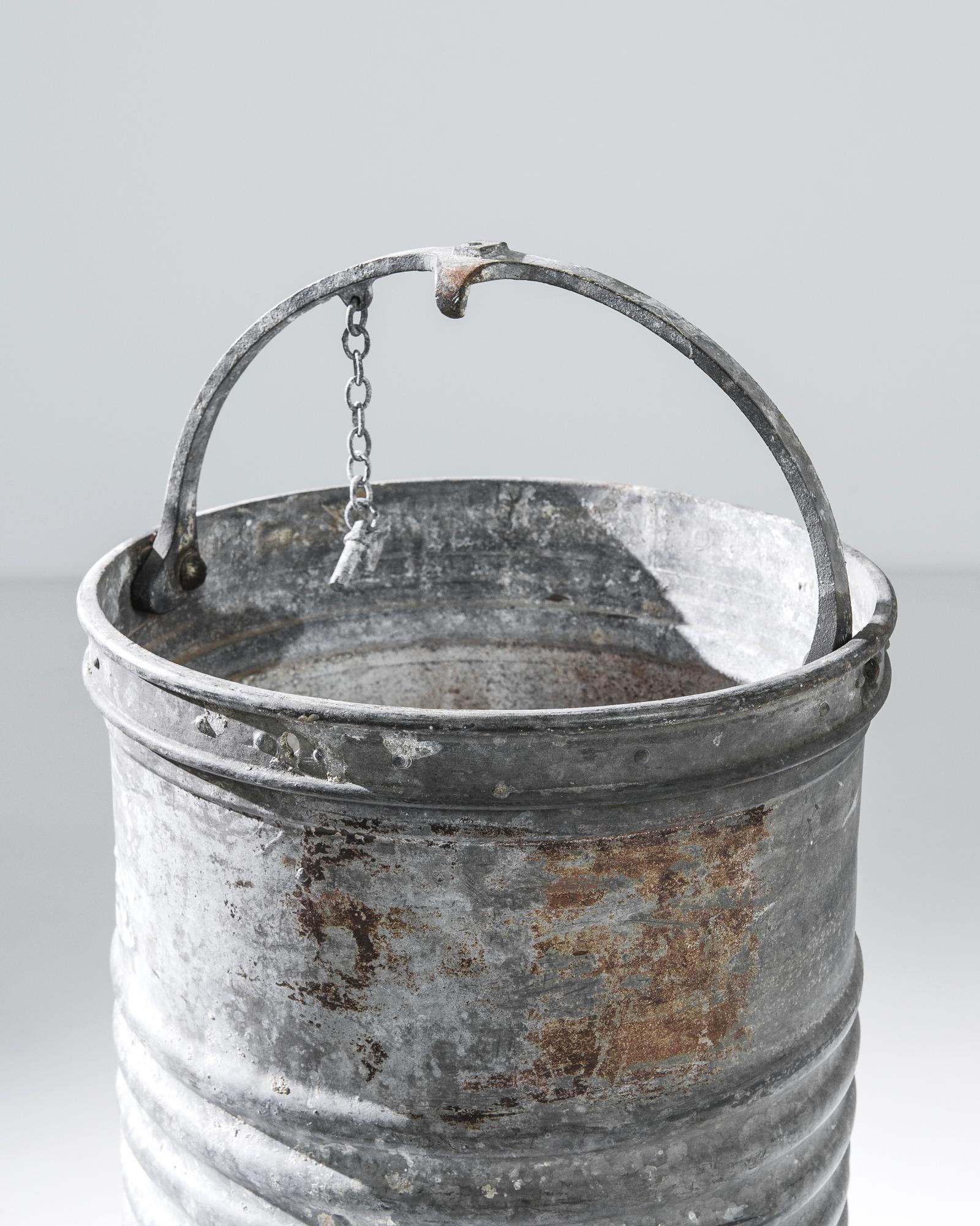 This 1950s French Zinc Bucket is a perfect blend of functionality and vintage charm. Its galvanized surface, worn by time, reveals a history of hard work and reliability. The sturdy handle, equipped with a wood grip, adds a touch of rustic warmth to
