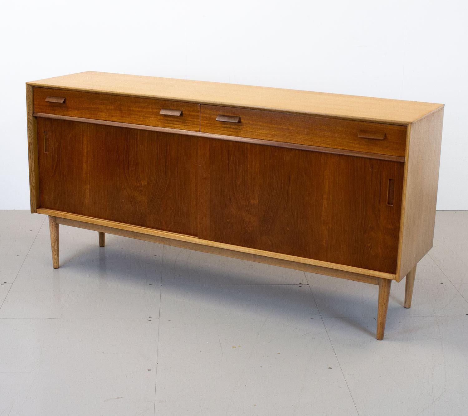 Rare G Plan sideboard by E Gomme. Part of the Group 3 range, it was designed by Richard Young in the early 1960s who later went on to form Merrow Associates. Minimal in design it has an oak frame, teak sliding doors and drawers with afromosia detail