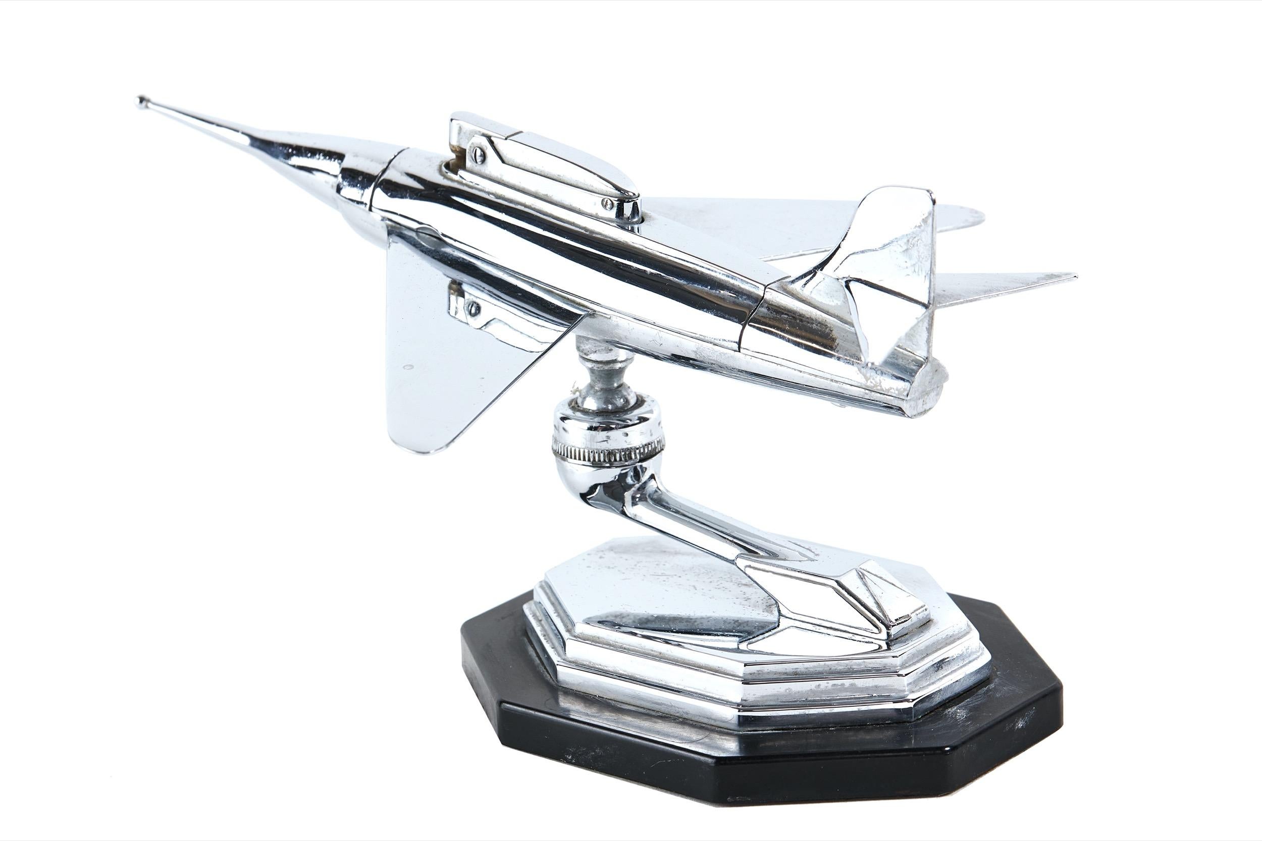Vintage Chrome plated table lighter, in the form of a 
 Jet fighter Plane circa 1950
Cigarette lighter cased in the planes body, [ball catch]
Stylised Bracket to hold swivel ball, to show fighter plane in 
numerous manoeuvres
Sitting on black