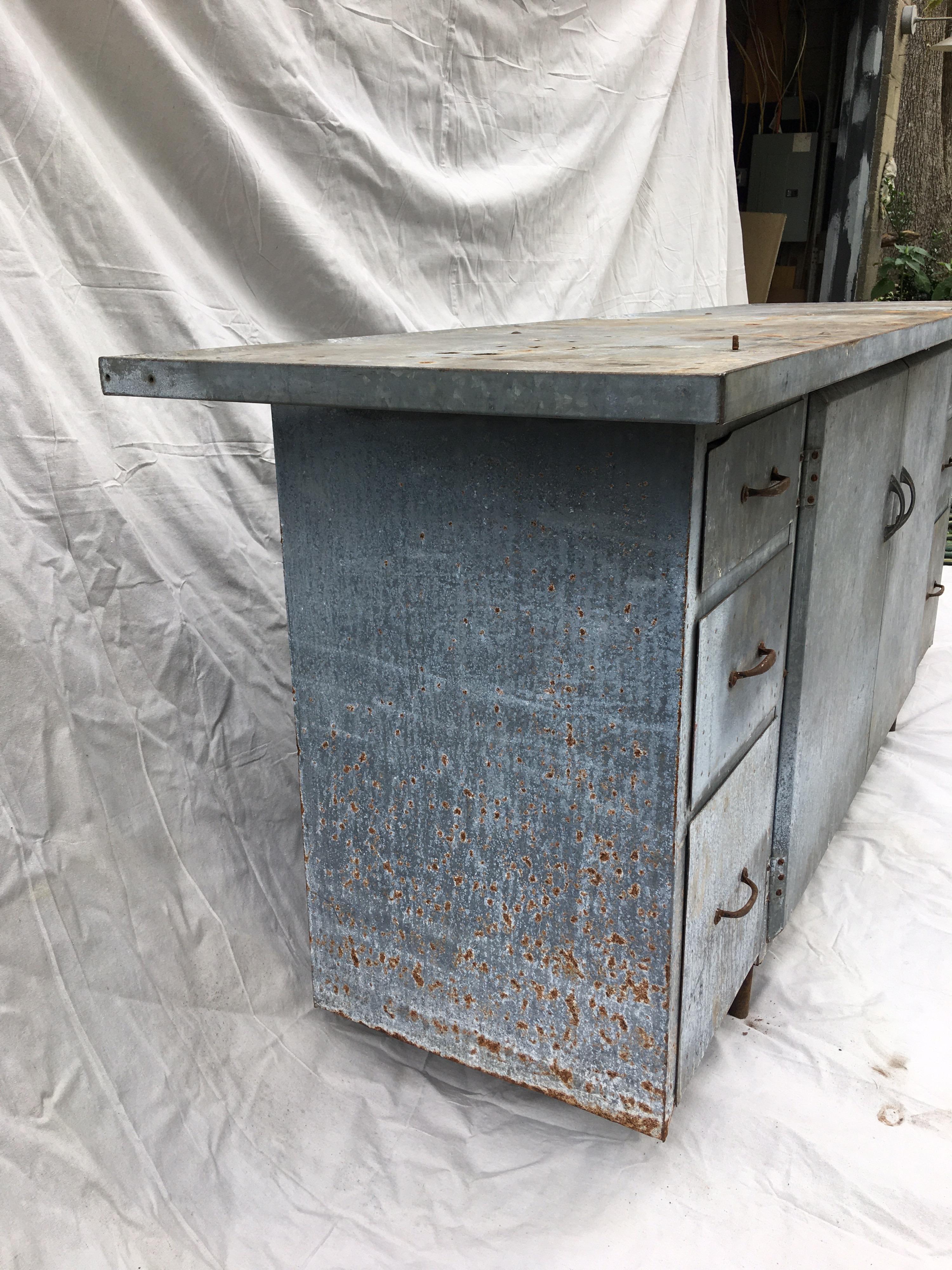 Galvanized Industrial work bench perfect to use as a kitchen Island, garden work table or credenza! Patina galvanized metal shows tons of personality! Drawers on each side with 2 large center doors that open to one large shelf. Top has an edge and