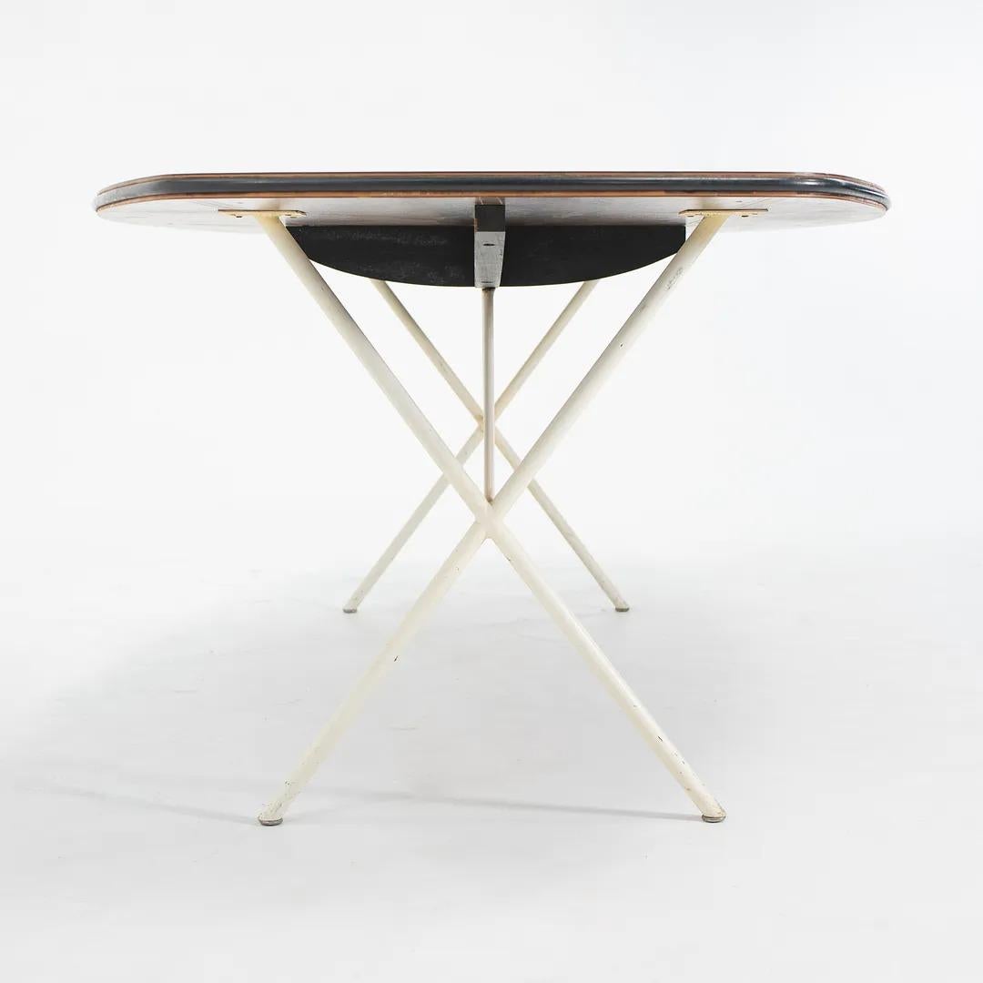 This is a Soft Edge Curved Dining Table, model 5259, designed by George Nelson for Herman Miller in 1953. The piece has a walnut top and white enameled steel legs, and this particular silhouette was only produced for a short time between 1953 and