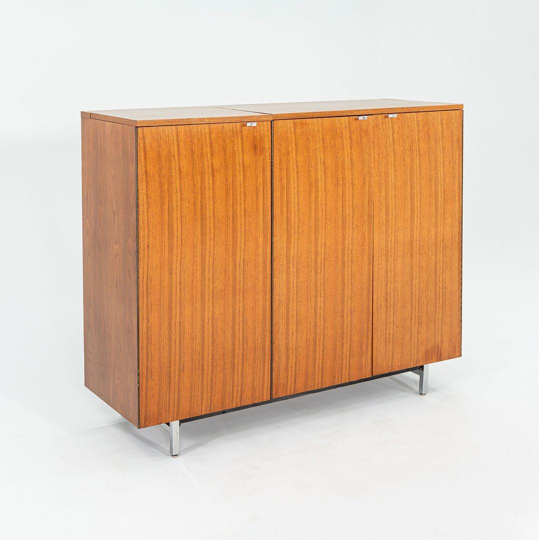 This is a Three-Door Basic Cabinet Series bar in walnut, initially designed by George Nelson for Herman Miller in 1946. This particular piece was produced ca.1950. Three cabinet doors have solid full-length hinges, and the original pulls are