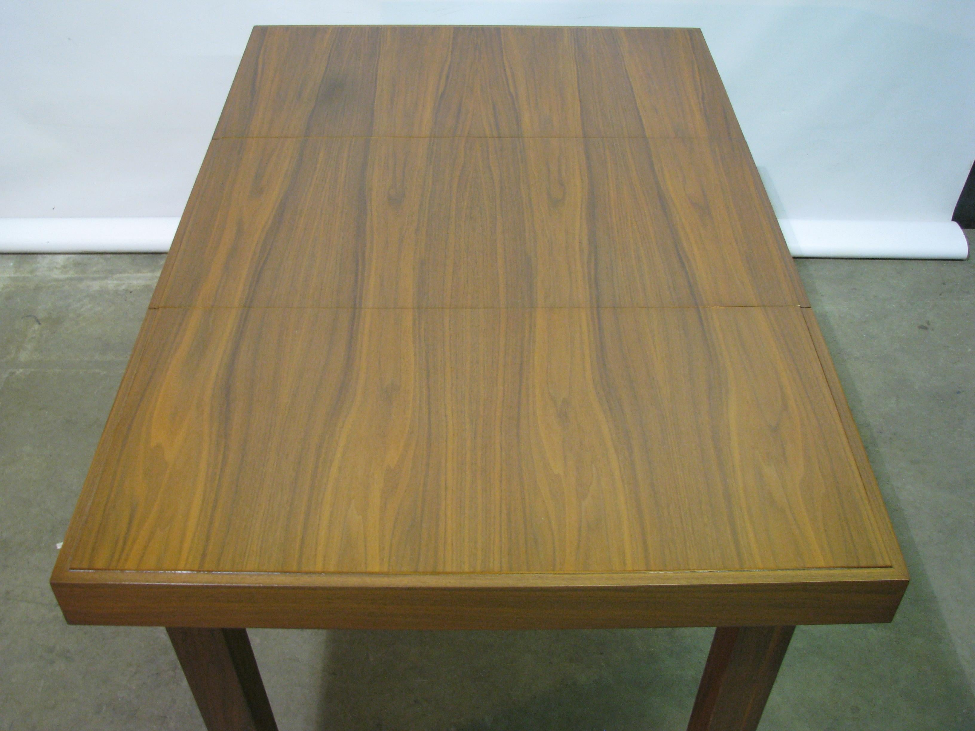Scarce 1950s dining table with self-storing leaves by George Nelson for Herman Miller. Striking walnut veneers that are continuous across the three top sections of the main table. A 3.25