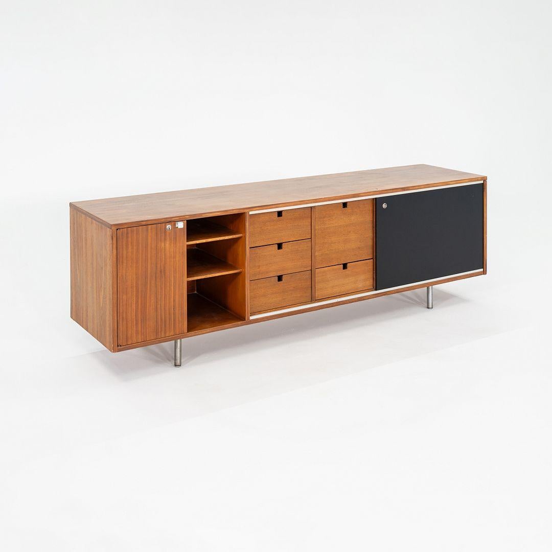Il s'agit d'une crédence en noyer conçue par George Nelson pour Herman Miller. Cet exemple particulier a été produit aux États-Unis et date des années 1950. La crédence se compose d'une caisse en noyer avec portes et tiroirs coulissants, soutenue