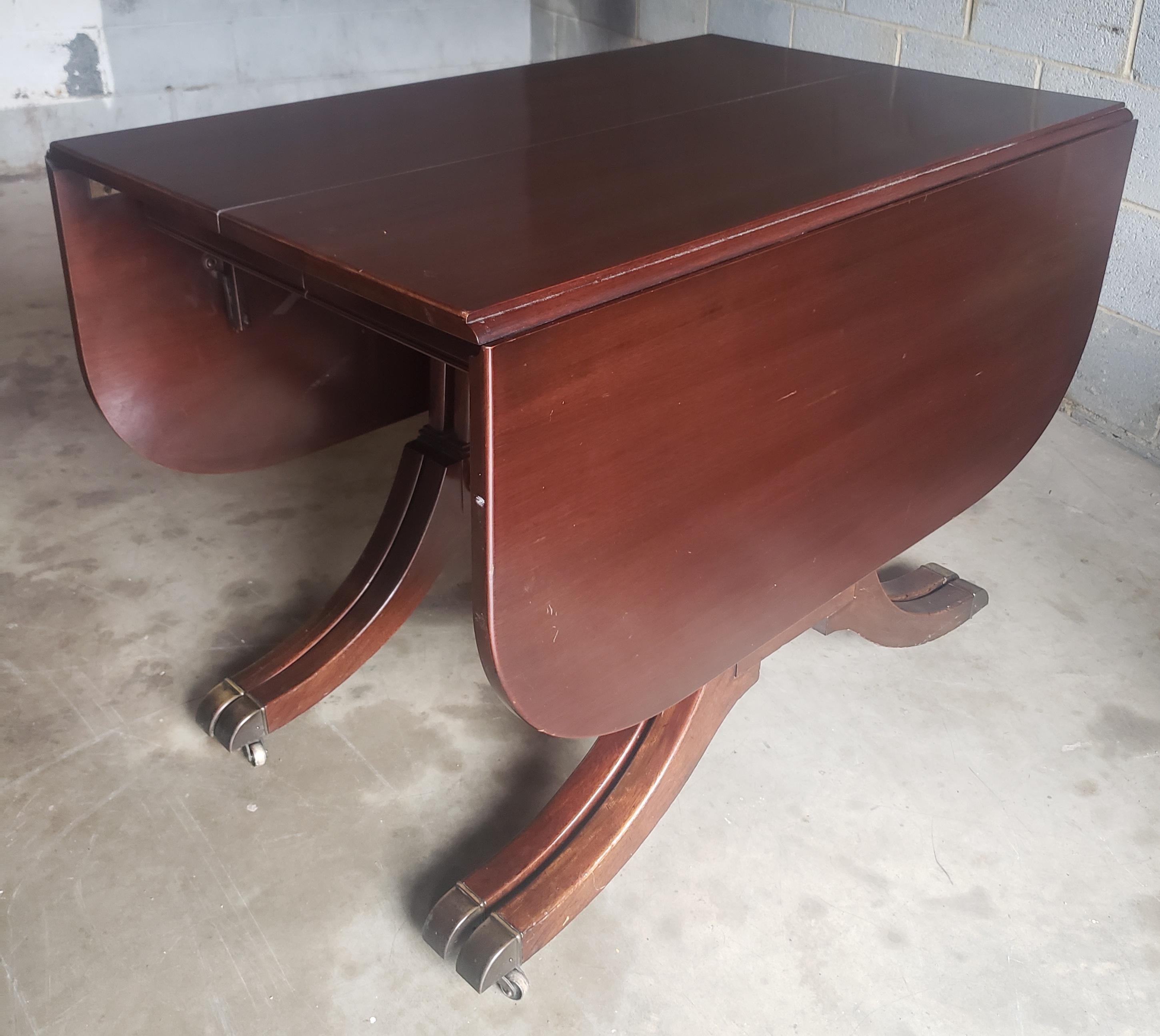 A 1950s George III Style Mahogany Drop Leaf Dining Table by iconic Georgetown Galleries. Features 4 pedestals all on original solid wheels. Recently refinished and in very good condition. Measures 26.5