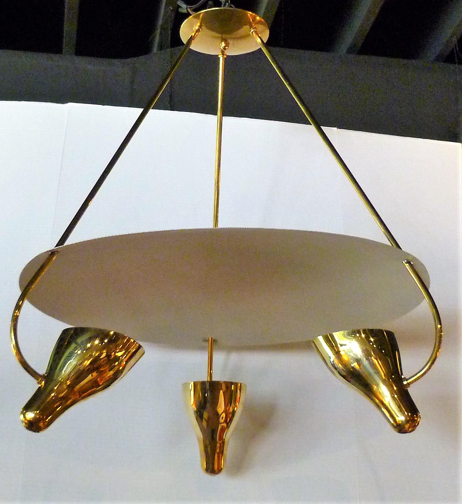 An inspired design by Gerald Thurston and produced by Lightolier, this chandelier uses reflection as a means of light with it's three brass cones that pierce a curving powder-coated metal canopy above them, their up beams of light radiating down