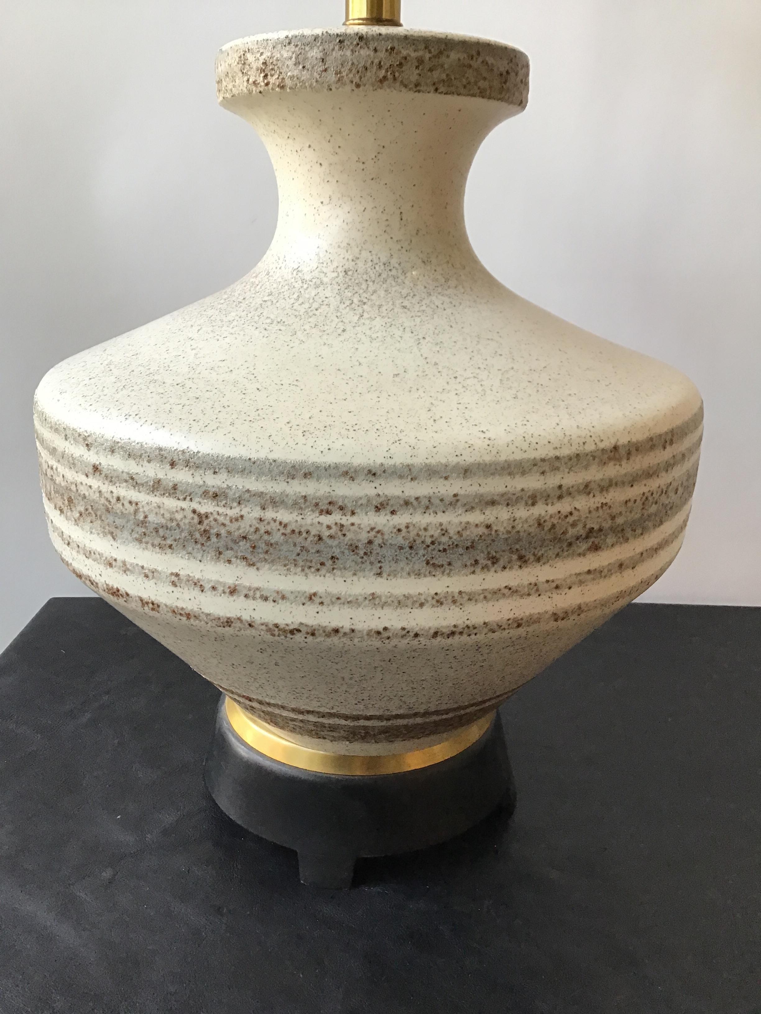1950s Gerald Thurston ceramic lamp on wood and brass base. Ivory glazed porcelain lamps with speckled horizontal stripes.