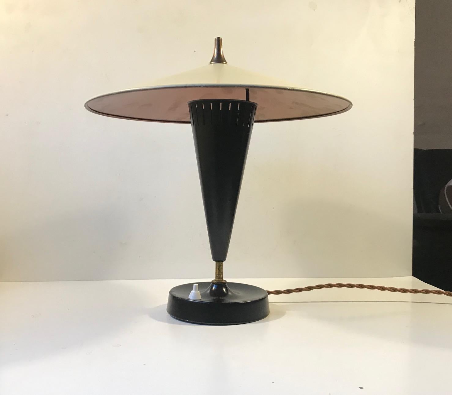 Very early unidentified German table light. It is fashioned out of aluminium, brass and bakelite. The shade has been restored and refinished at some point. The slightly yellowish main-shade has a copper lacquer applied to the inside. This gives a