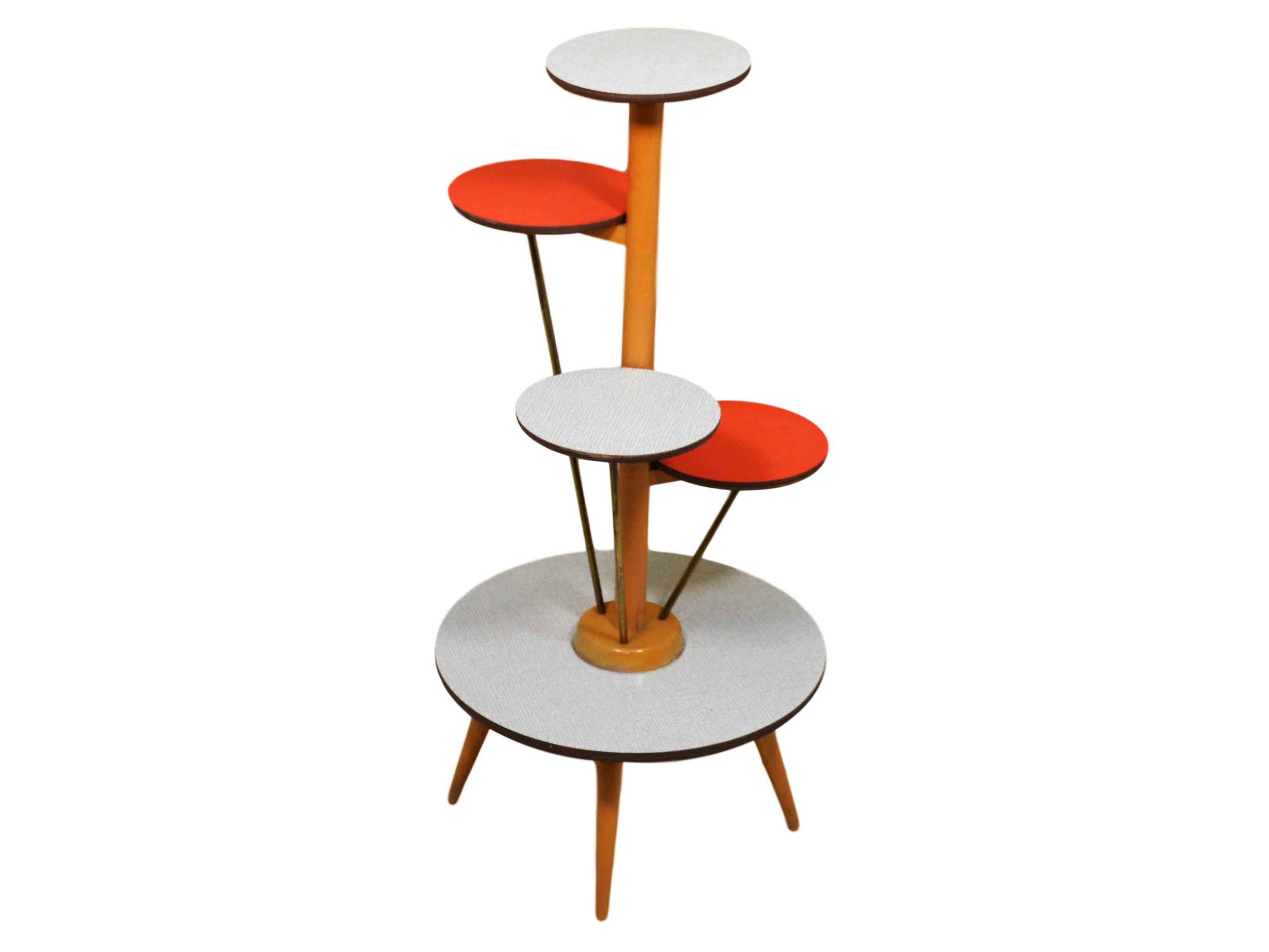 This is a 5-tier 1950s German plant stand. Made by Ilse Möbel. Great for displaying plants or ornaments. Two of the tiers are red. The base, middle and top tier are white with gray plaid pattern.

Very good condition. There is a small chip on the