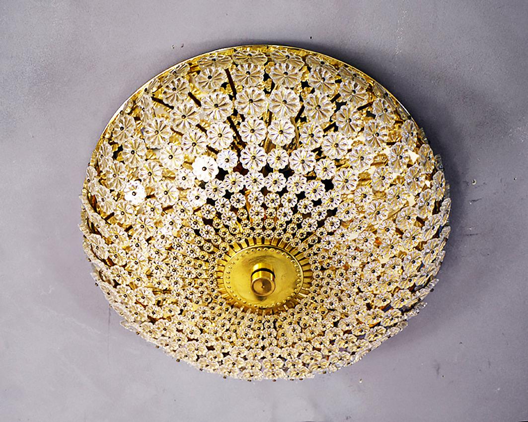 Elegant large flush mount with small glass flowers on a brass frame. Chandelier illuminates beautifully and offers a lot of light. Gem from the time. With this light you make a clear statement in your interior design. A real eye-catcher even unlit.