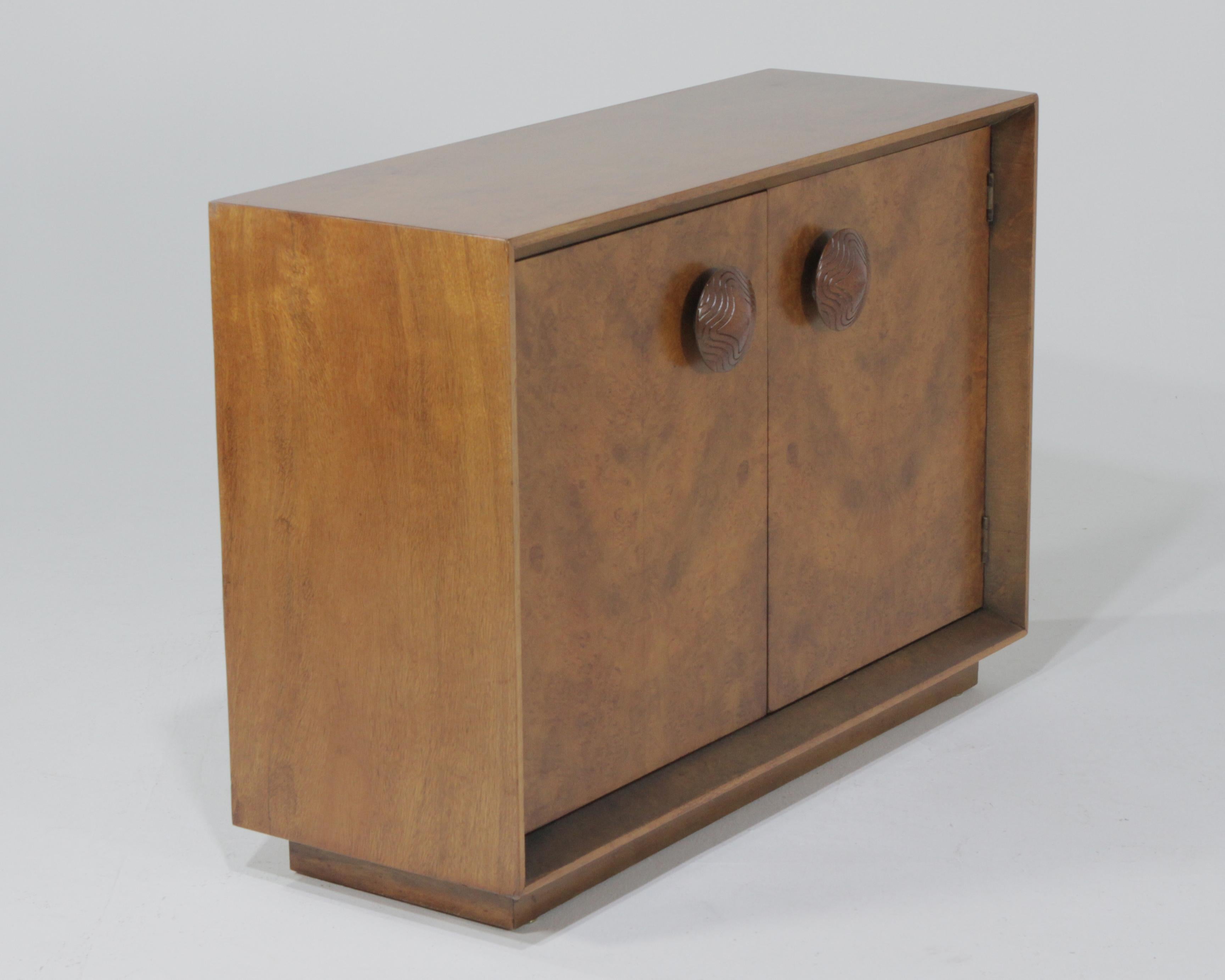 A wonderful Paldao cabinet designed by Gilbert Rohde for Herman Miller. It has all the iconic features, the oversized pulls, burl front and large recess. One shelf in the interior.