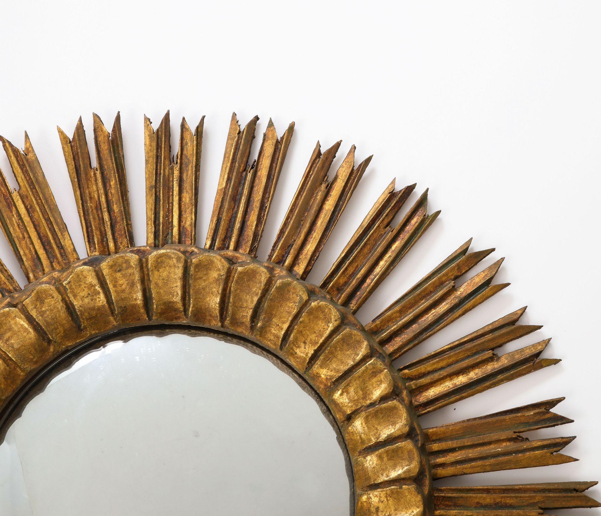 A 1950s small French sunburst mirror. The classic sunburst frame is made of giltwood and has mirror plate with age appropriate patina. Wear consistent with age and use.