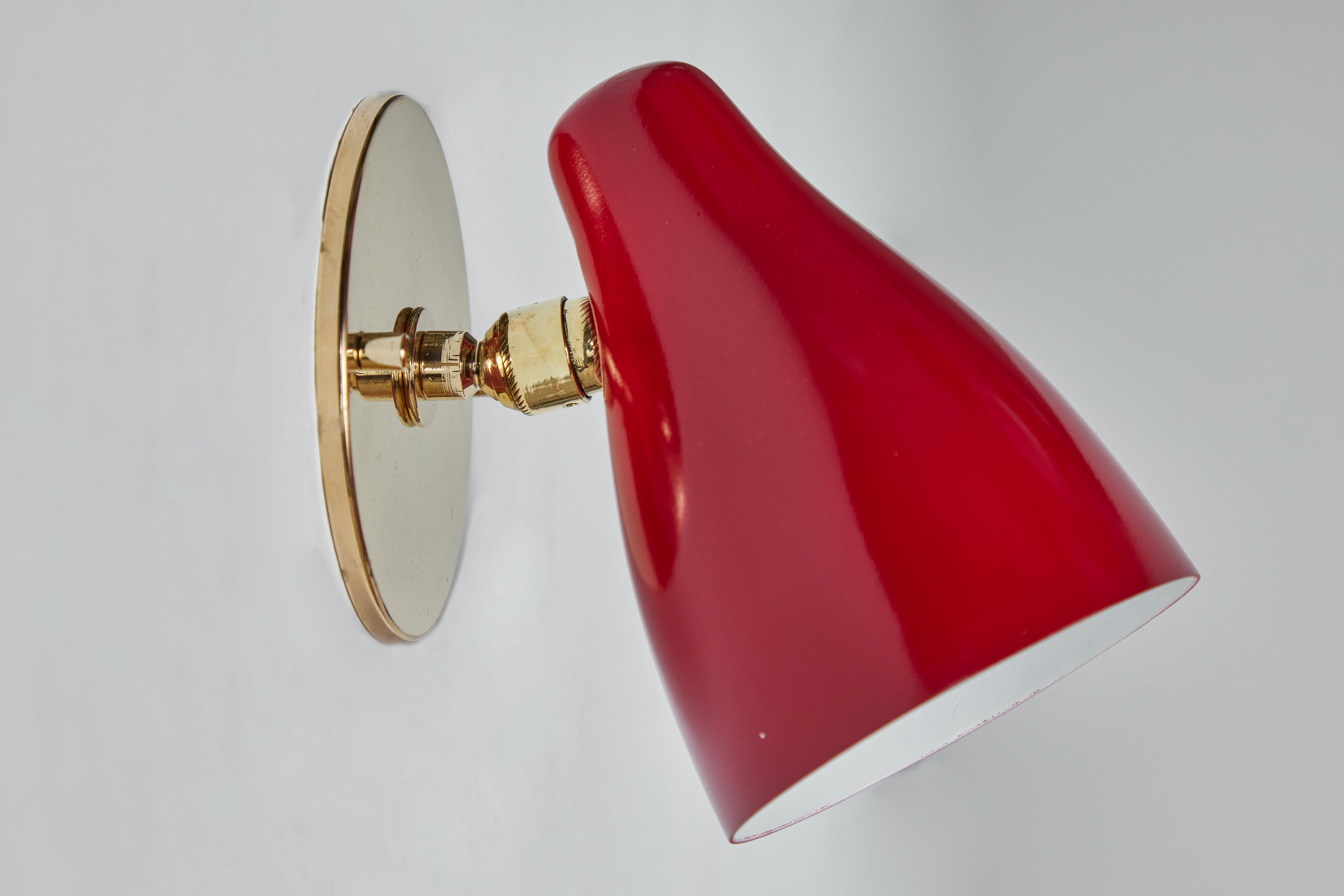 1950s Gino Sarfatti articulating red wall lamp for Arteluce. Executed in red painted metal and brass. Ball jointed arm connection to shade allows for flexible shade adjustments and multiple configurations. The simplicity of Sarfatti's design and the