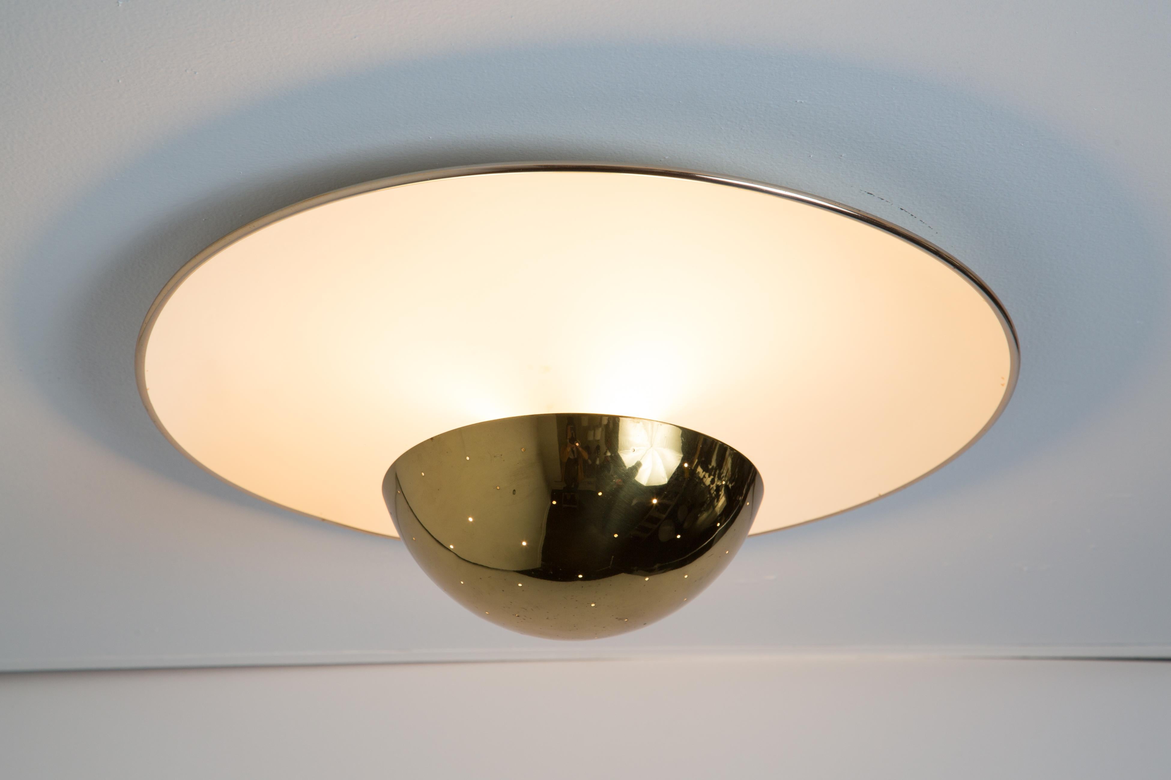 1950s Gino Sarfatti model #155 ceiling lamp for Arteluce. A perforated brass dome on a white painted metal curved plate with a brass detail on the edge. An extremely attractively scaled ceiling or wall light of incomparably refined design. Arteluce