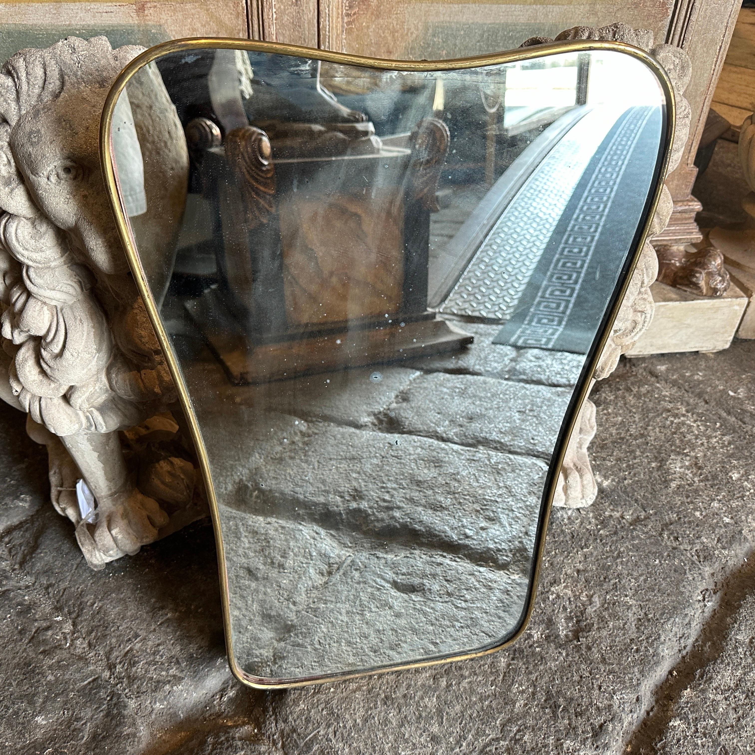 An amazing mid-century modern biscuit shaped wall mirror hand-crafted in Italy in the Fifties in the manner of Gio Ponti which he used these wall mirrors to furnish the most prestigious homes in Milan in the 1950s. The mirror brass frame it's in