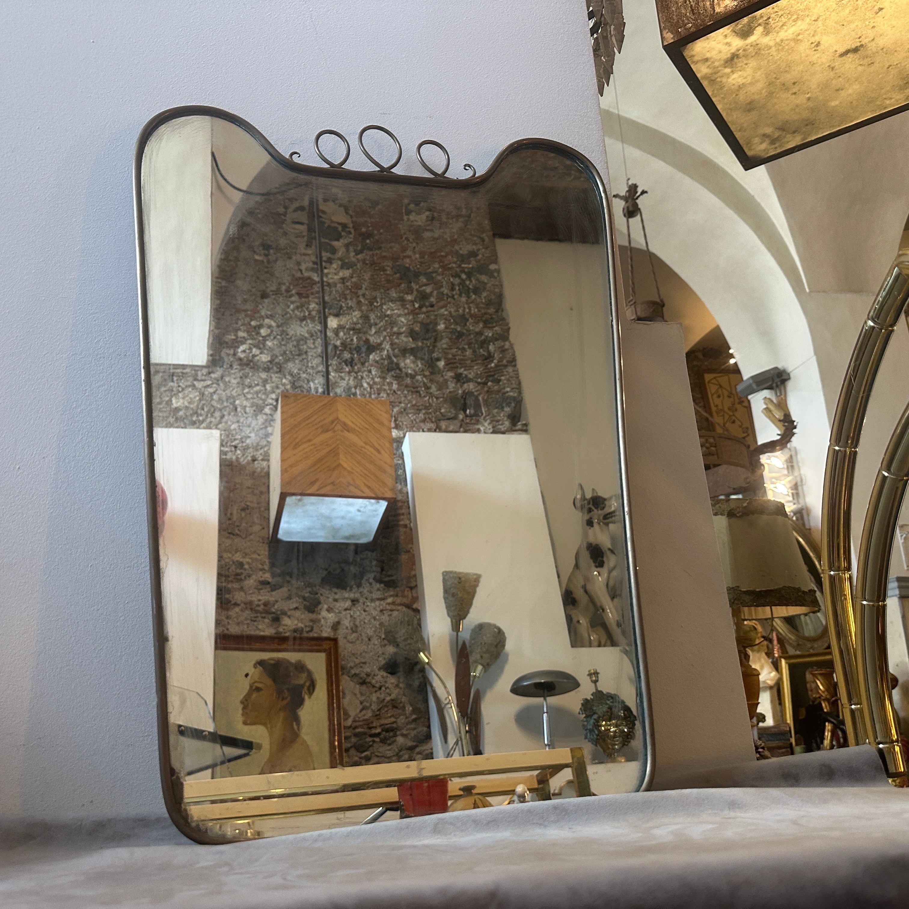 An amazing mid-century modern biscuit shaped solid brass wall mirror hand-crafted in Italy in the Fifties in the manner of Gio Ponti which he used these wall mirrors to furnish the most prestigious homes in Milan in the 1950s. The mirror it's in