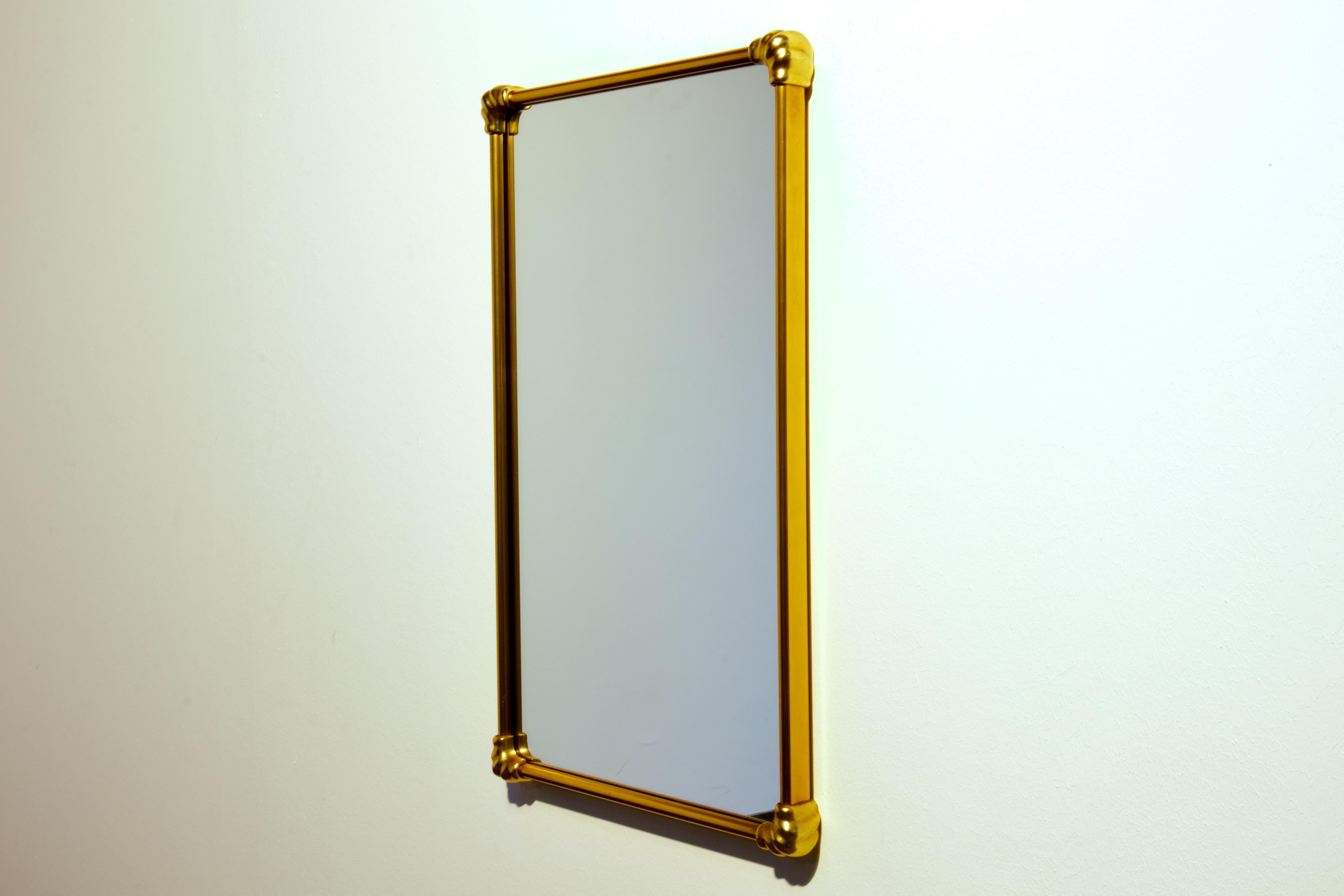 Gio Ponti era Mid-Century Modern wall mirror in patinated brass. Made in Italy in 1950s.

The shape of the mirror is a rectangle with straight brass sides and solid brass corner elements that have an elegant curvaceous form.

The wall mount is