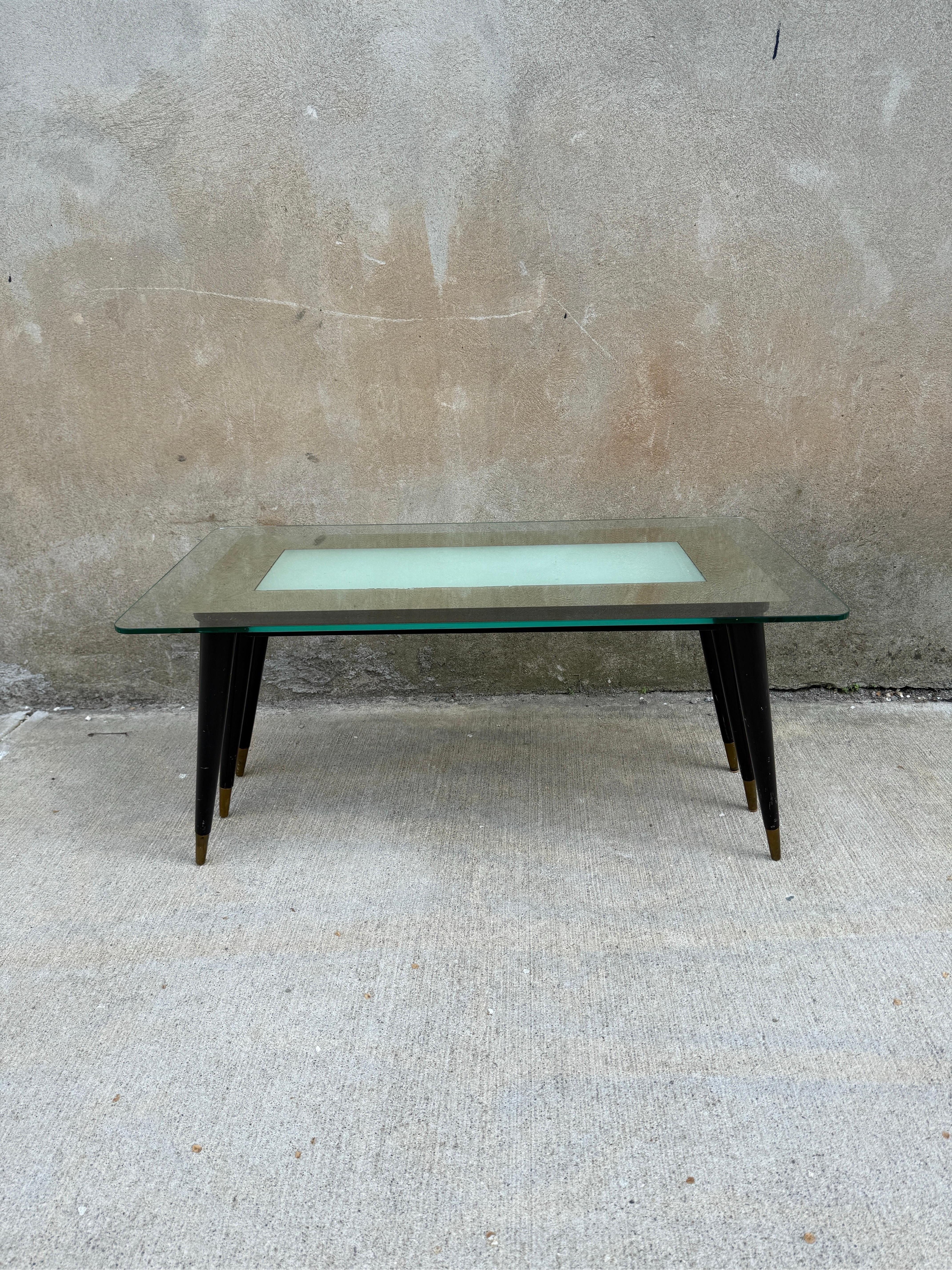 Exemple extrêmement rare d'une table basse à six pieds attribuée à Gio Ponti, fabriquée en Italie dans les années 1950.  Six pieds noirs avec des capuchons en laiton soutiennent un plateau séparé en verre miroir avec un centre opaque.  Il faut