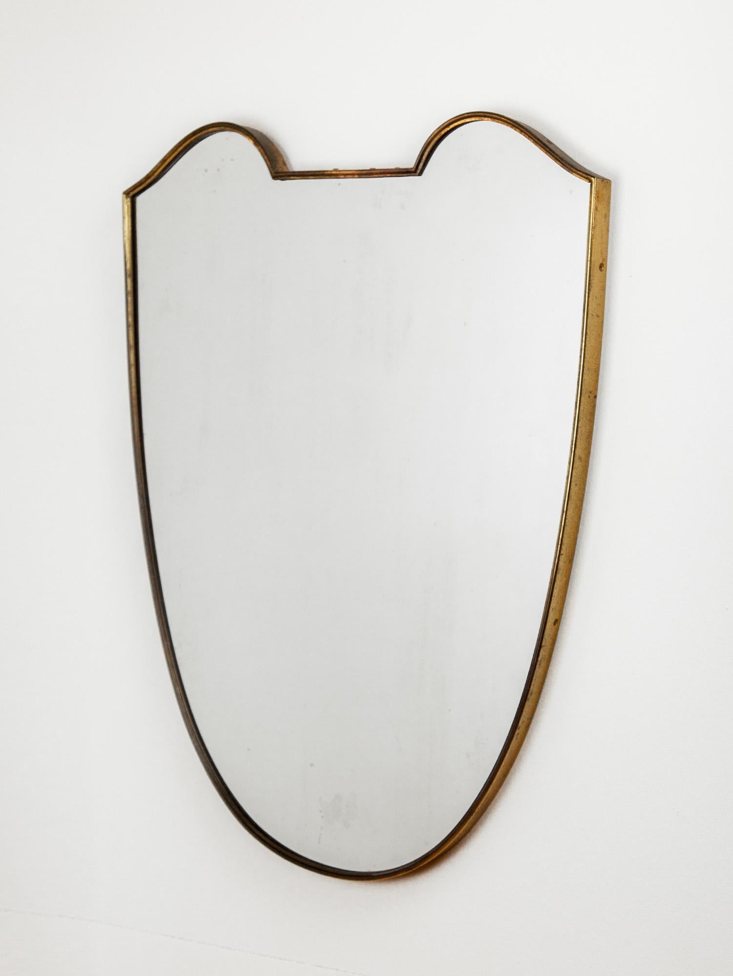 Vintage Italian brass mirror with a brass surround in the style of Gio Ponti. The classic shape epitomizes Italian modernist design. The brass frame holds the glass and wooden backing with a hidden hook on the underside. Made circa the 1950s.

Great