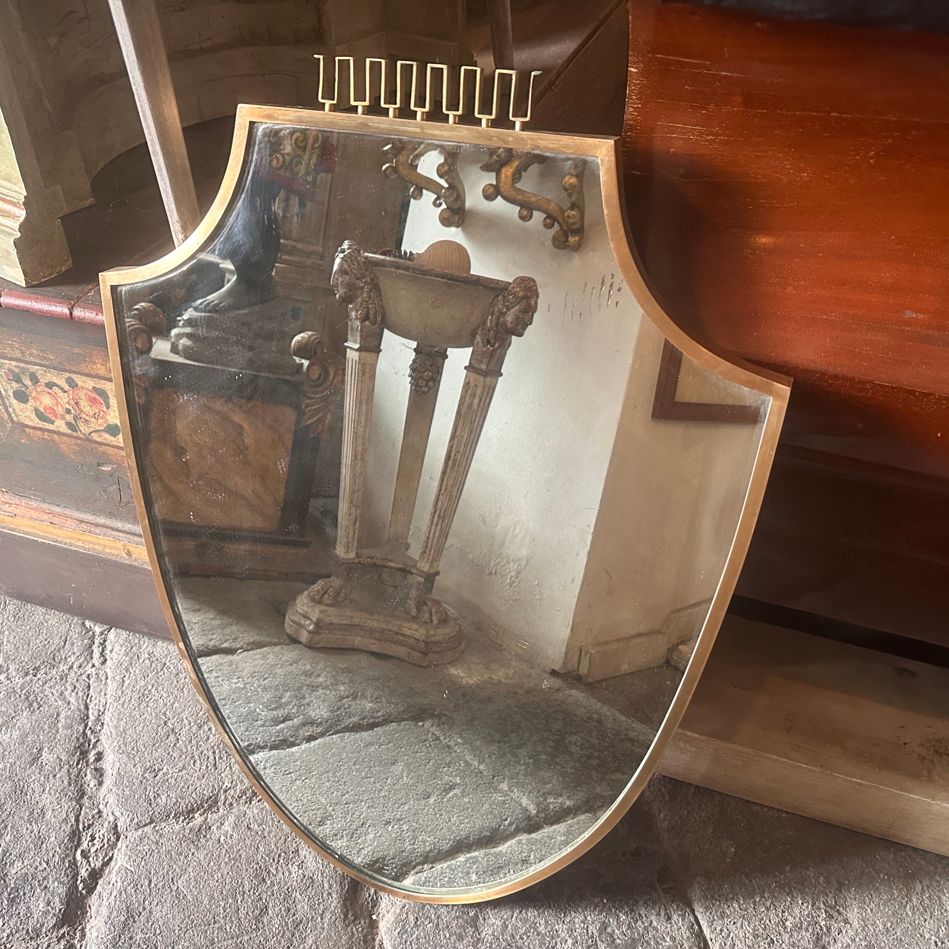 An amazing solid brass wall mirror designed and manufactured in Italy in the manner of Gio Ponti who used this type of mirror in the most beautiful houses in Milan in the 50s, brass it's in a lovely original patina, glass it's the original one. The