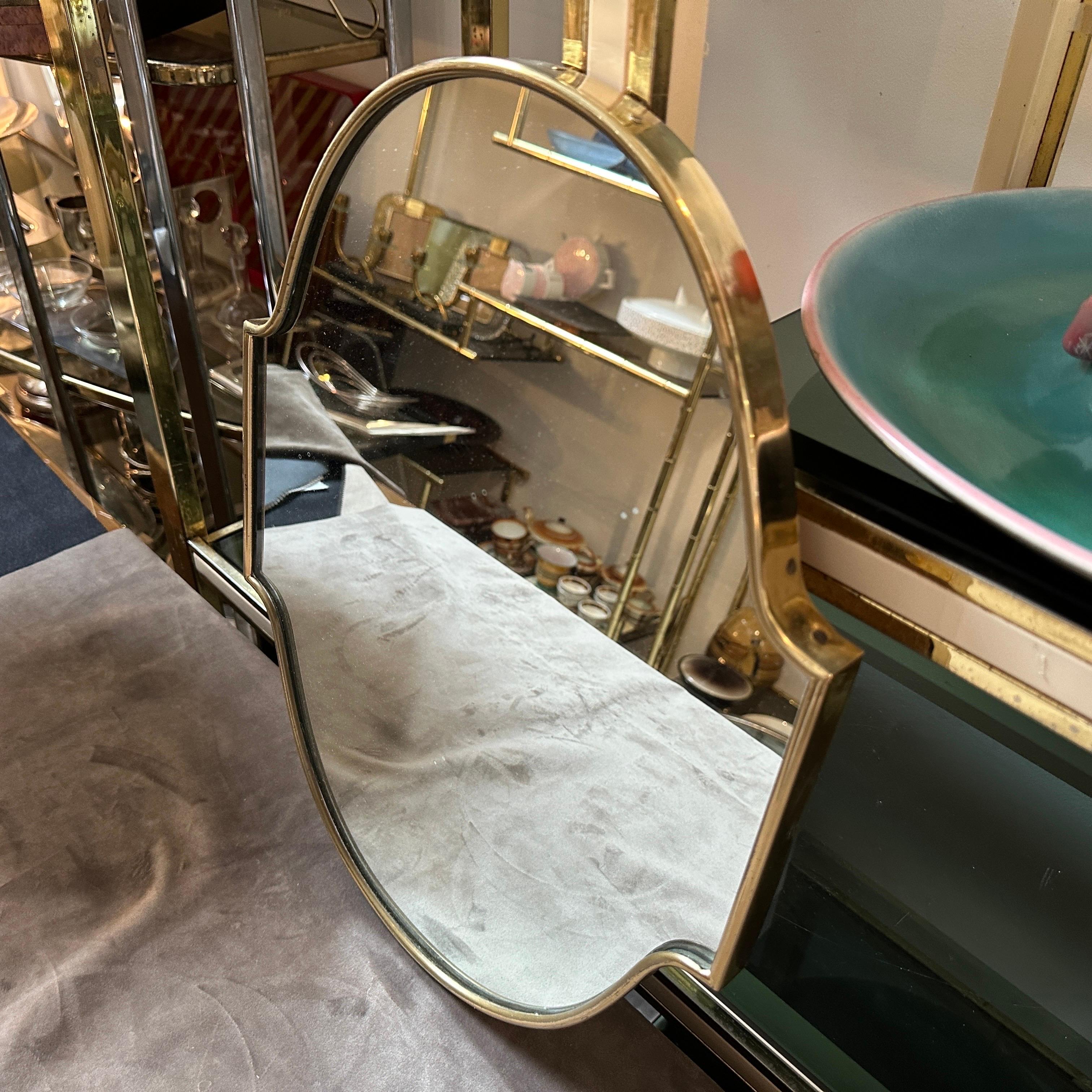 A solid brass wall mirror designed and manufactured in Italy in the Fifties in the manner of Gio Ponti, it's in good conditions overall. The wall mirror is a stunning piece of vintage design that embodies the essence of mid-century aesthetics.