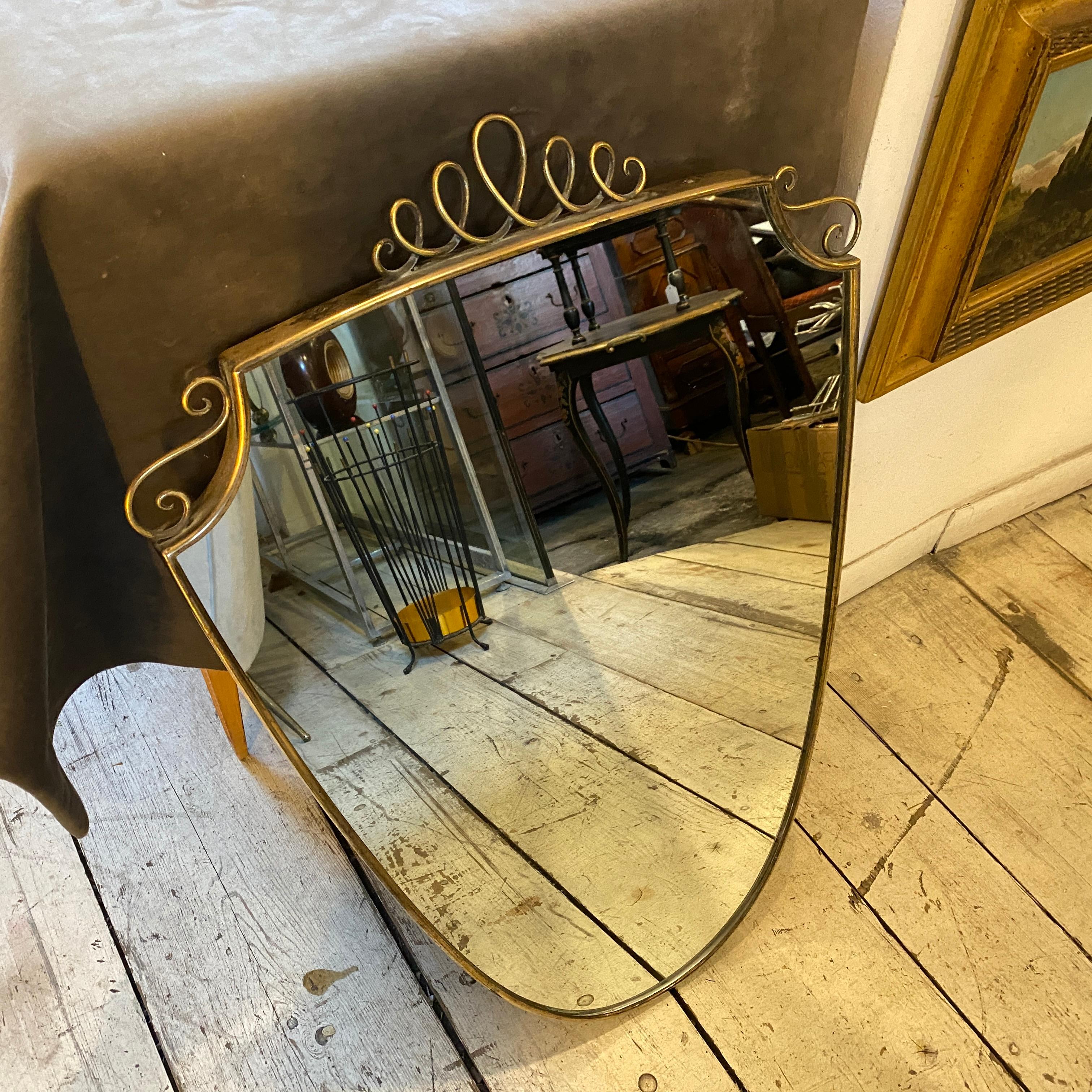 A stylish solid brass shield wall mirror based on the mirrors of Giò Ponti. It has been made in Italy in the Fifties, original rear and mirror, brass it's in original patina, glass it's in perfect condition
