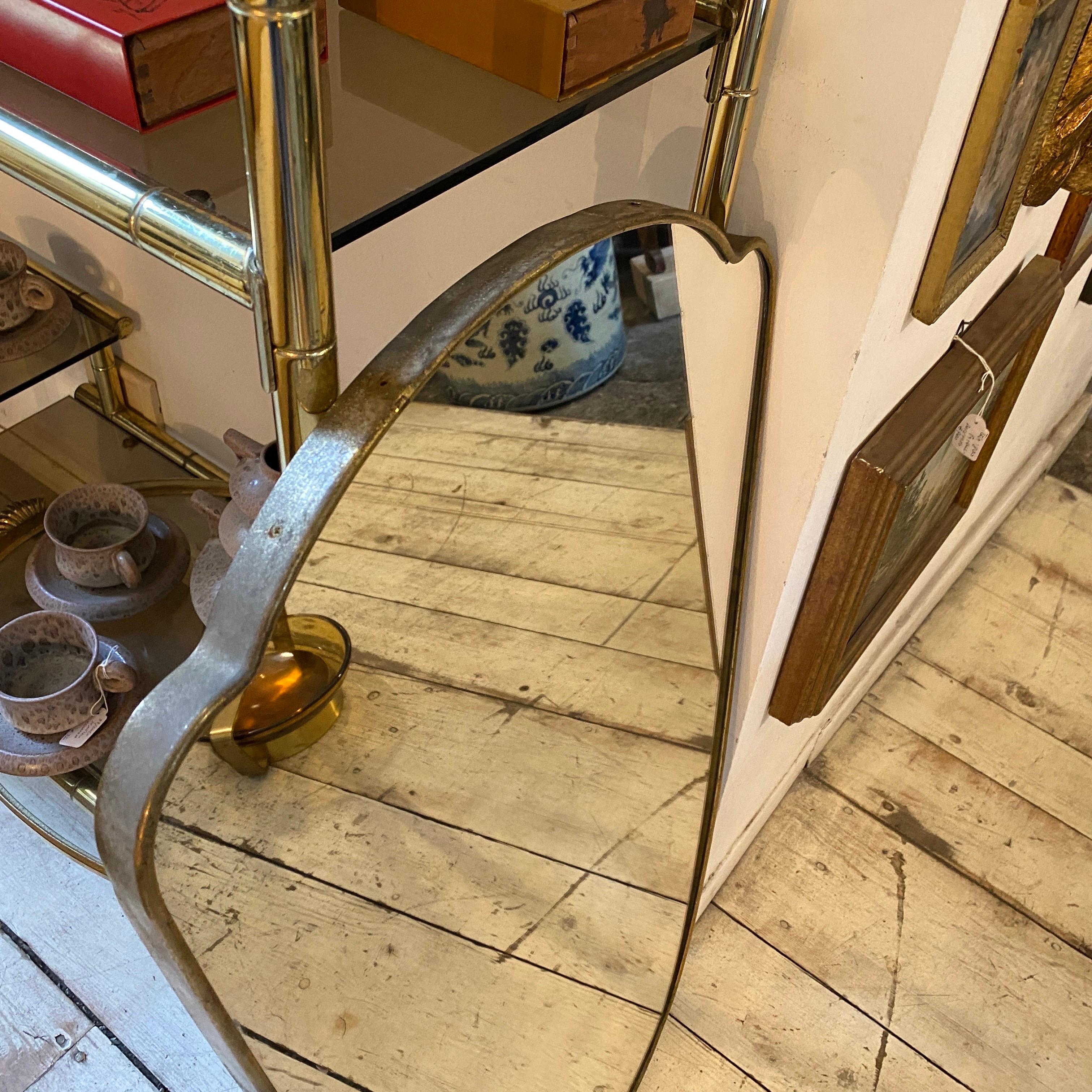 An original patina solid brass wall mirror manufactured in Italy in the Fifties in the manner of Giò Ponti. The glass it's in perfect conditions. The original patina brass gives it a vibrant vintage look.