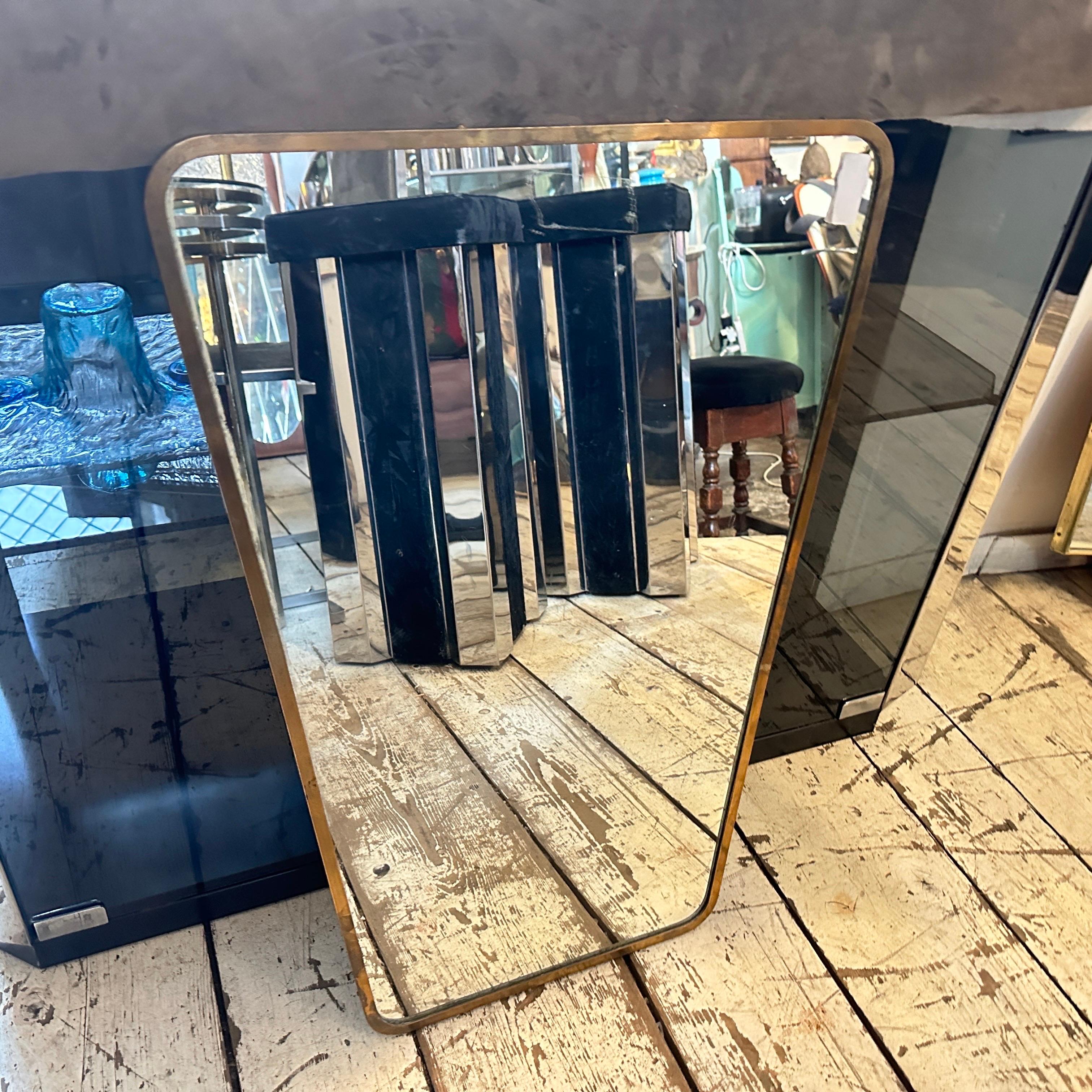 A solid brass wall mirror designed and manufactured in Italy in the manner of Gio Ponti, who used this type of mirror in the most beautiful houses in Milan in the 50s. The brass boasts a lovely original patina, while the glass remains original. This