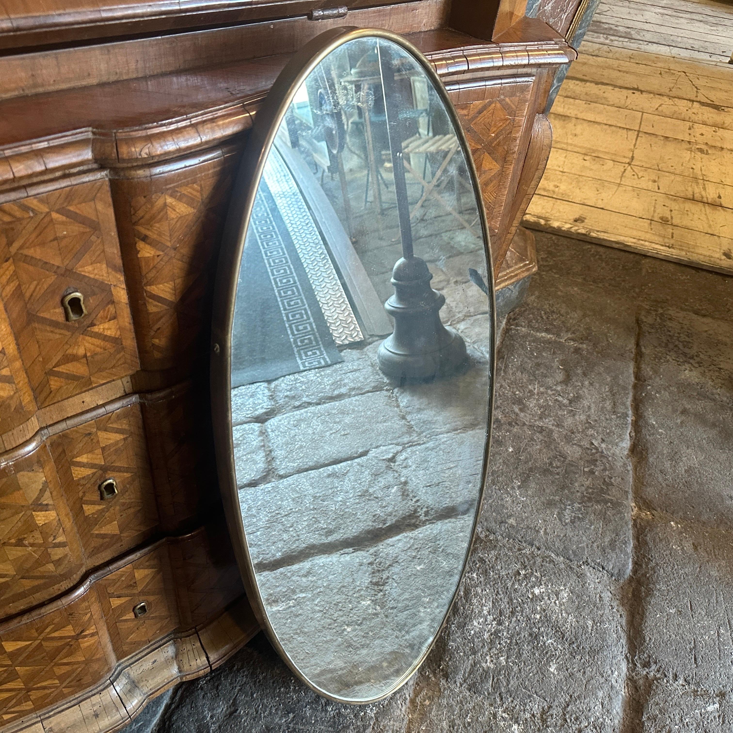 A solid brass wall mirror designed and manufactured in Italy in the Fifties, brass it's in original patina and has signs of use and age, mirror glass is the original one. The 1950s was a period of great creativity and innovation in the world of