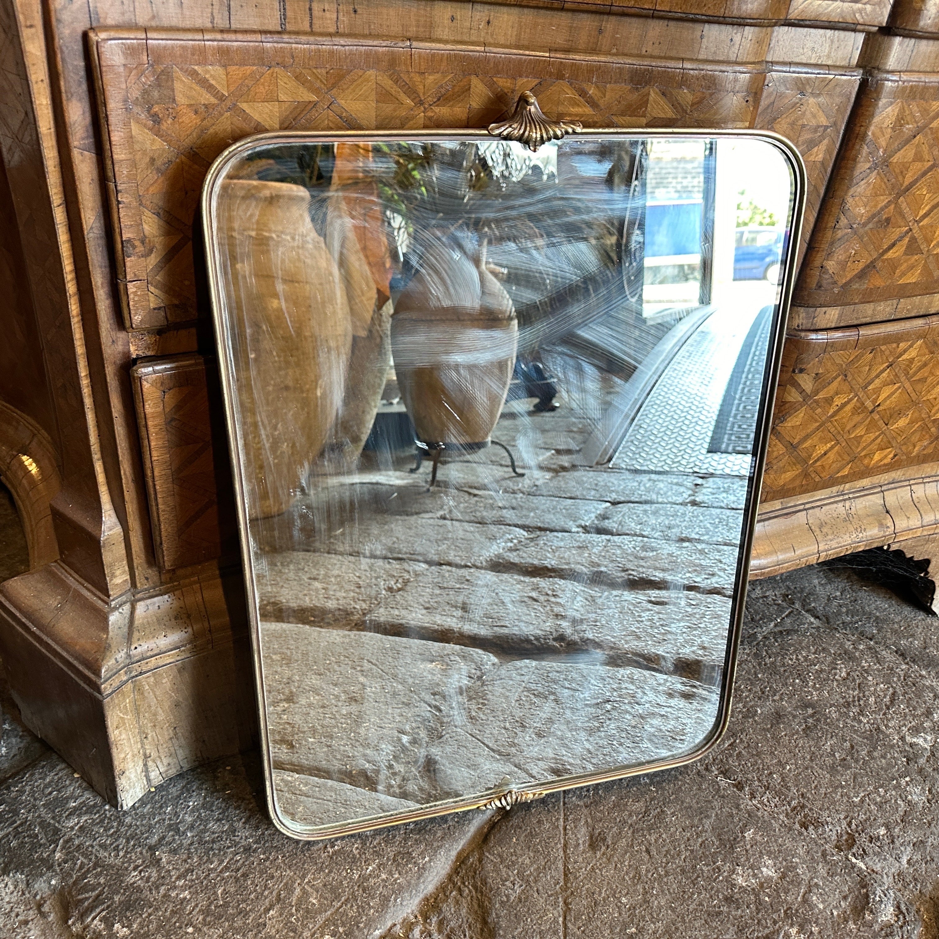 A solid brass wall mirror designed and manufactured in Italy in the manner of Gio Ponti, who used this type of mirror in the most beautiful houses in Milan in the 50s. The brass boasts a lovely original patina, while the glass remains original. The