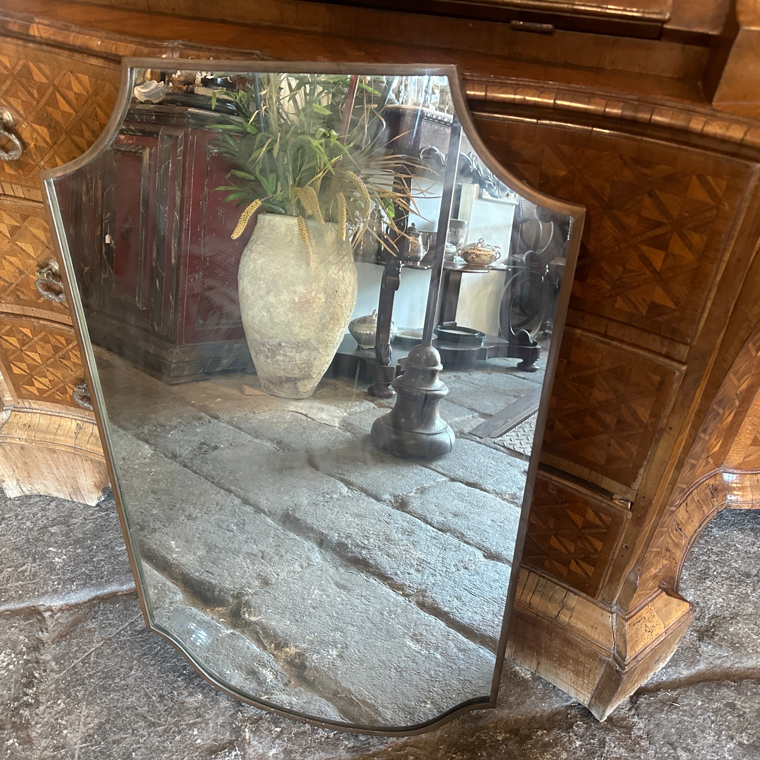 A solid brass wall mirror designed and manufactured in Italy in the manner of Gio Ponti who used this type of mirror in the most beautiful houses in Milan in the 50s, brass it's in a lovely original patina, glass it's the original one. The shield