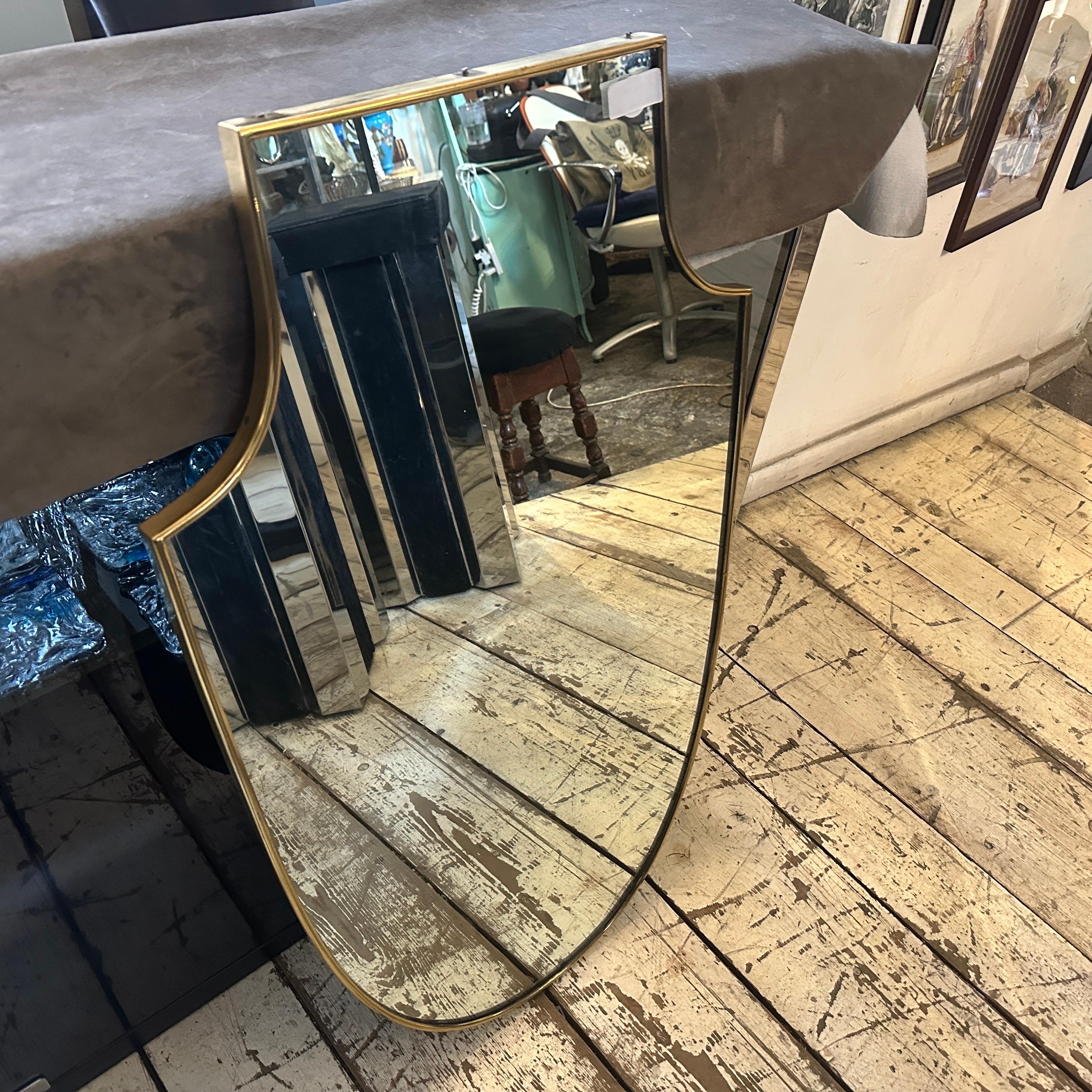 Uno specchio da parete in ottone massiccio progettato e realizzato in Italia alla maniera di Gio Ponti, che utilizzava questo tipo di specchio nelle più belle case milanesi degli anni '50. L'ottone vanta una bella patina originale, mentre il vetro