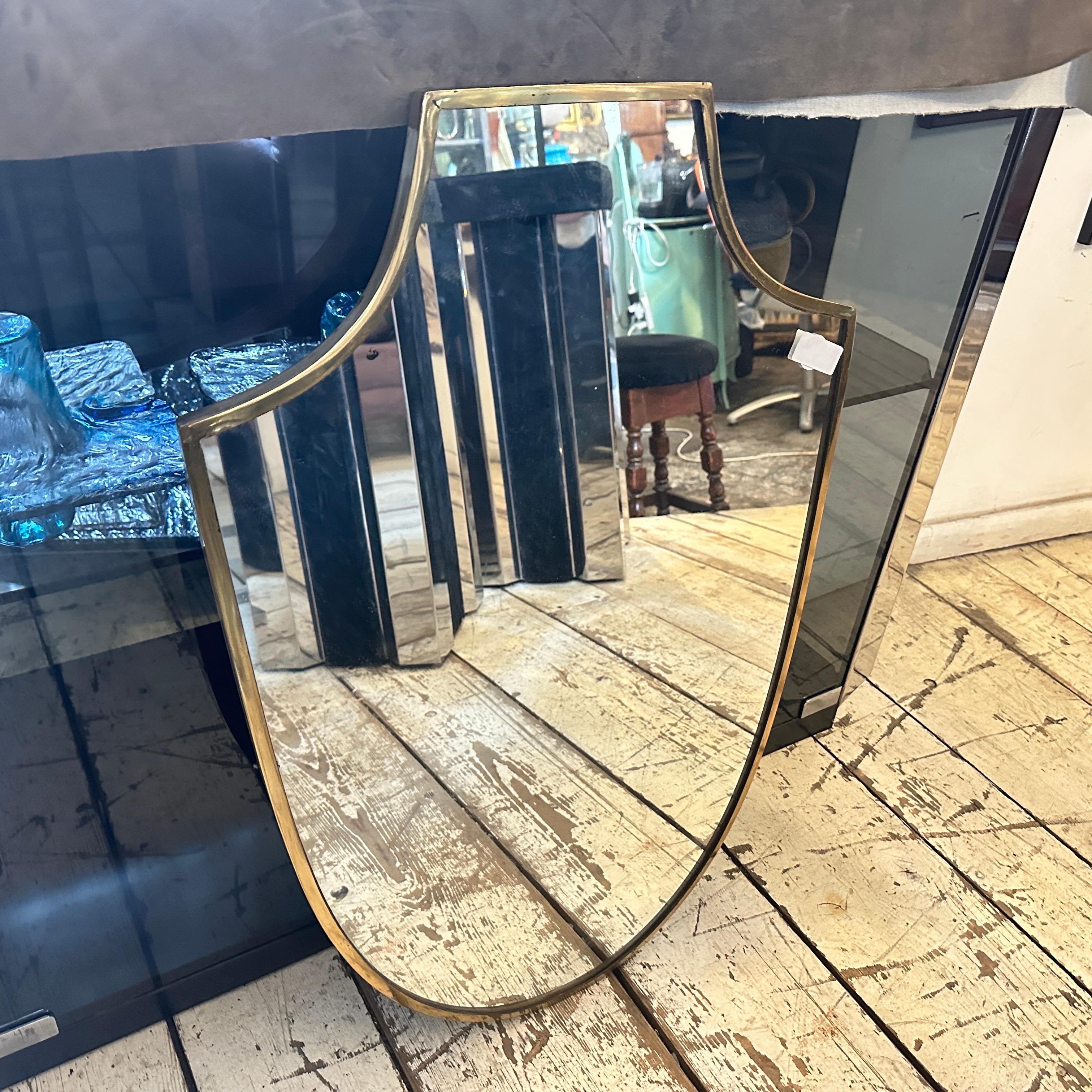 Uno specchio da parete in ottone massiccio progettato e realizzato in Italia alla maniera di Gio Ponti, che utilizzava questo tipo di specchio nelle più belle case milanesi degli anni '50. L'ottone vanta una bella patina originale, mentre il vetro