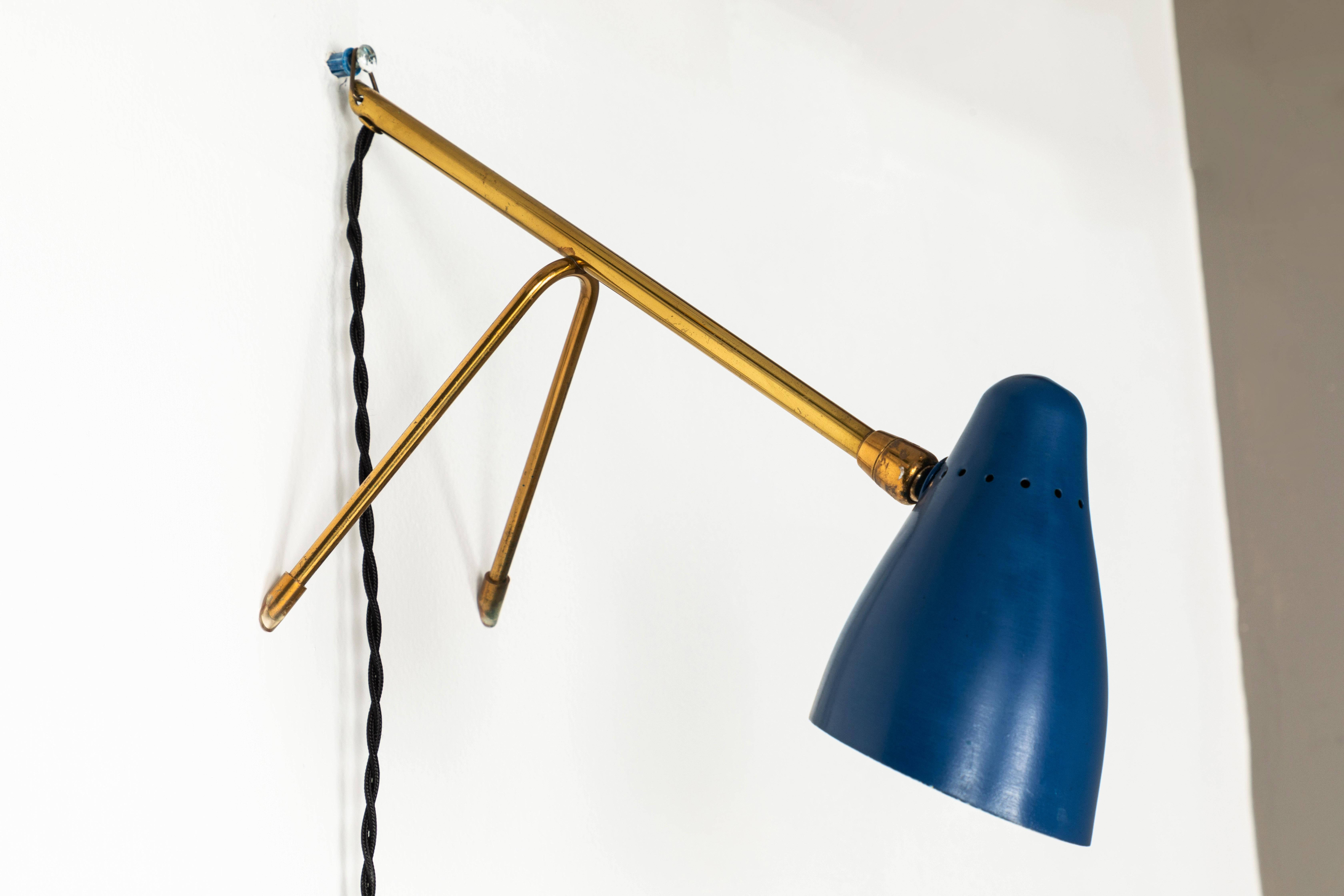 1950s Giuseppe Ostuni wall or table lamp for O-Luce . Executed in blue painted aluminum and brass. The shade sits on a brass ball joint giving it 360 degree tilting range for maximum adjustability. It also has a brass ring on the base for wall