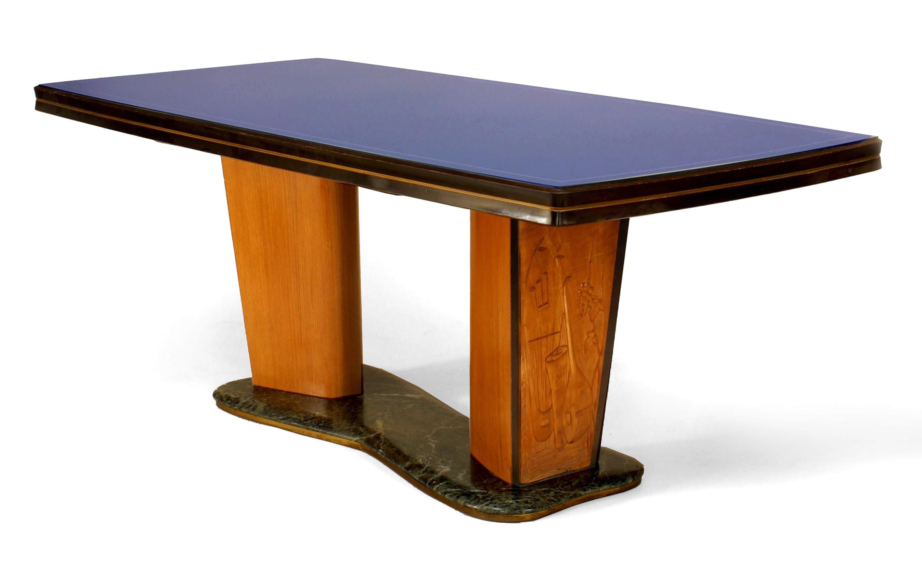Italian mid-century (1950s) walnut & maple dining table with a green free-form marble base supporting 2 carved pedestal bases with relief scene under a blue glass top (Attributed to Vittorio Dassi / Enzo Ferrari).
  