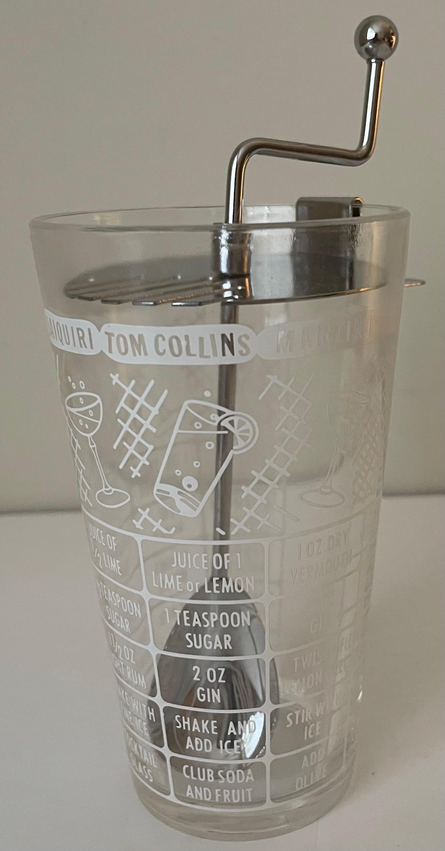 1950s Retro style cocktail shaker. Metal lid with attached spoon. Glass design features various retro cocktail receipies.