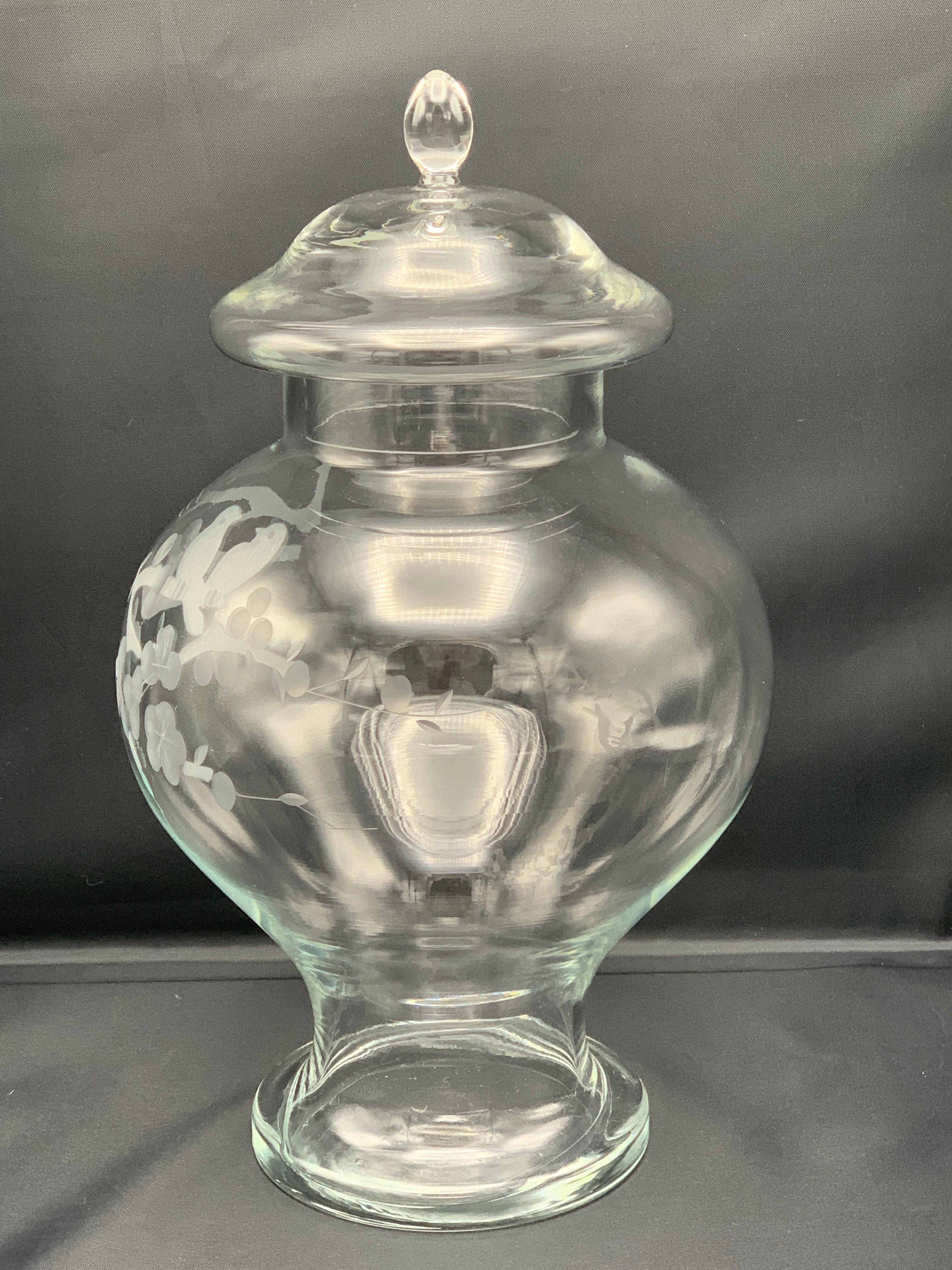 Offered is a gorgeous and rare, 1950s glass ginger jar. This exquisite piece has an ornate scene of a cherry blossom branch and bird motif hand-etched along the front side. Removable lid. Stunning condition, with no chips, cracks, or major