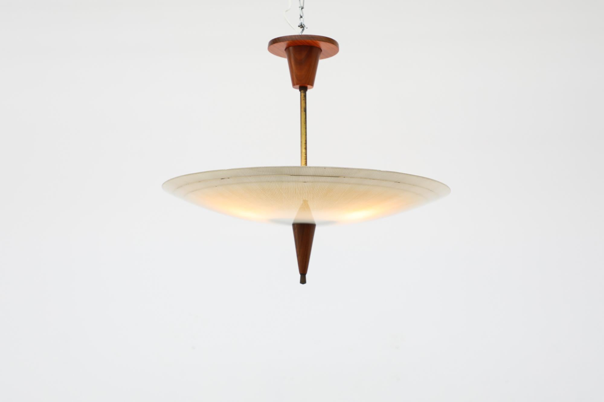 Beautiful 1950's Rondelle ceiling pendant with patterned glass and gold accented shade. The light features brass and teak details, including teak canopy. In original condition with visible wear consistent with its age and use.