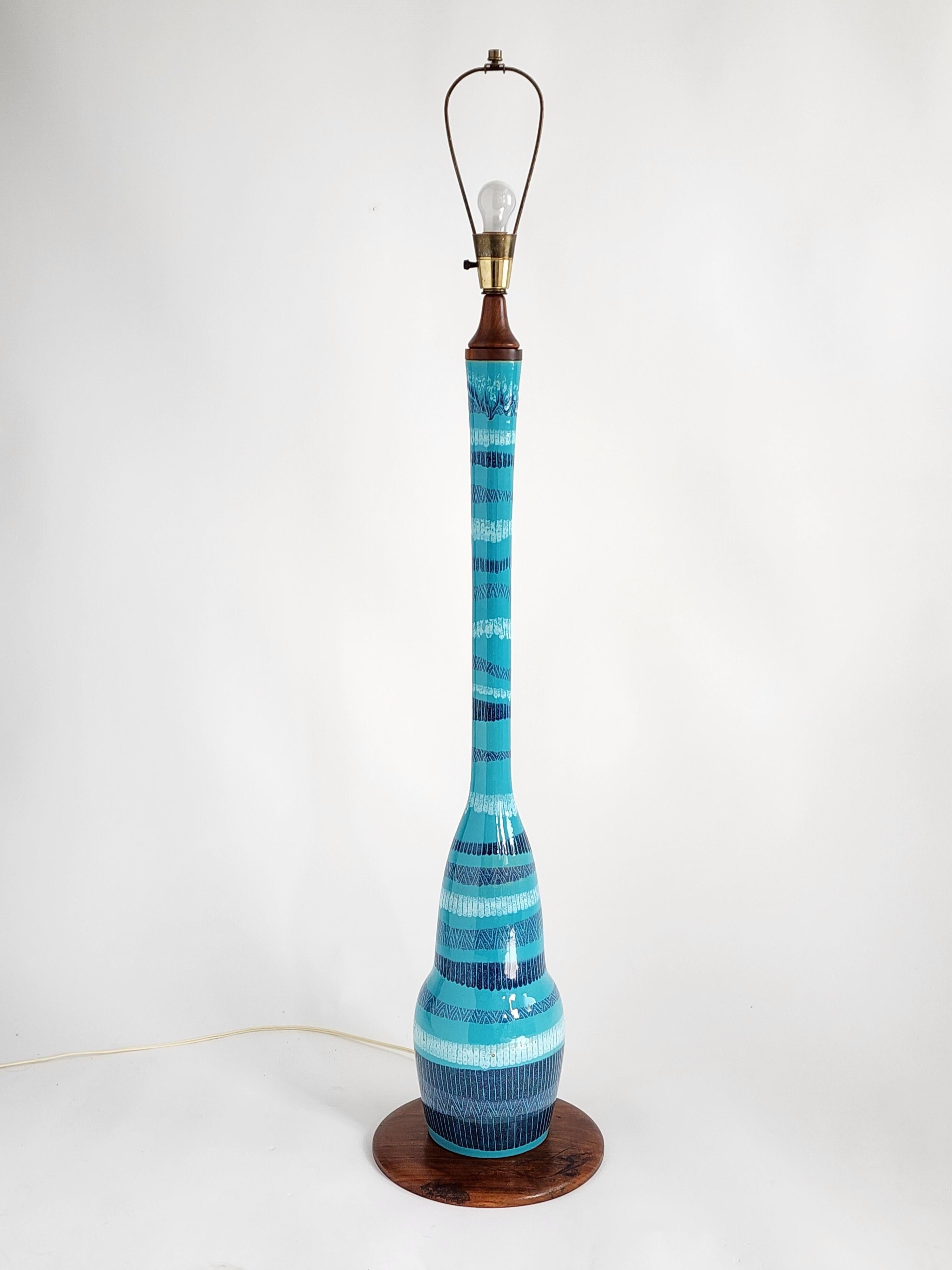 Huge glazed ceramic floor lamp in a tastefull blue tone variation sitting on a walnut base  

Prime quality material and hardware. 

Lamp mesure 55 in. to top arch 47 in. to socket. 

Walnut base is 12 in. wide. 

Ceramic base is 8 in. at