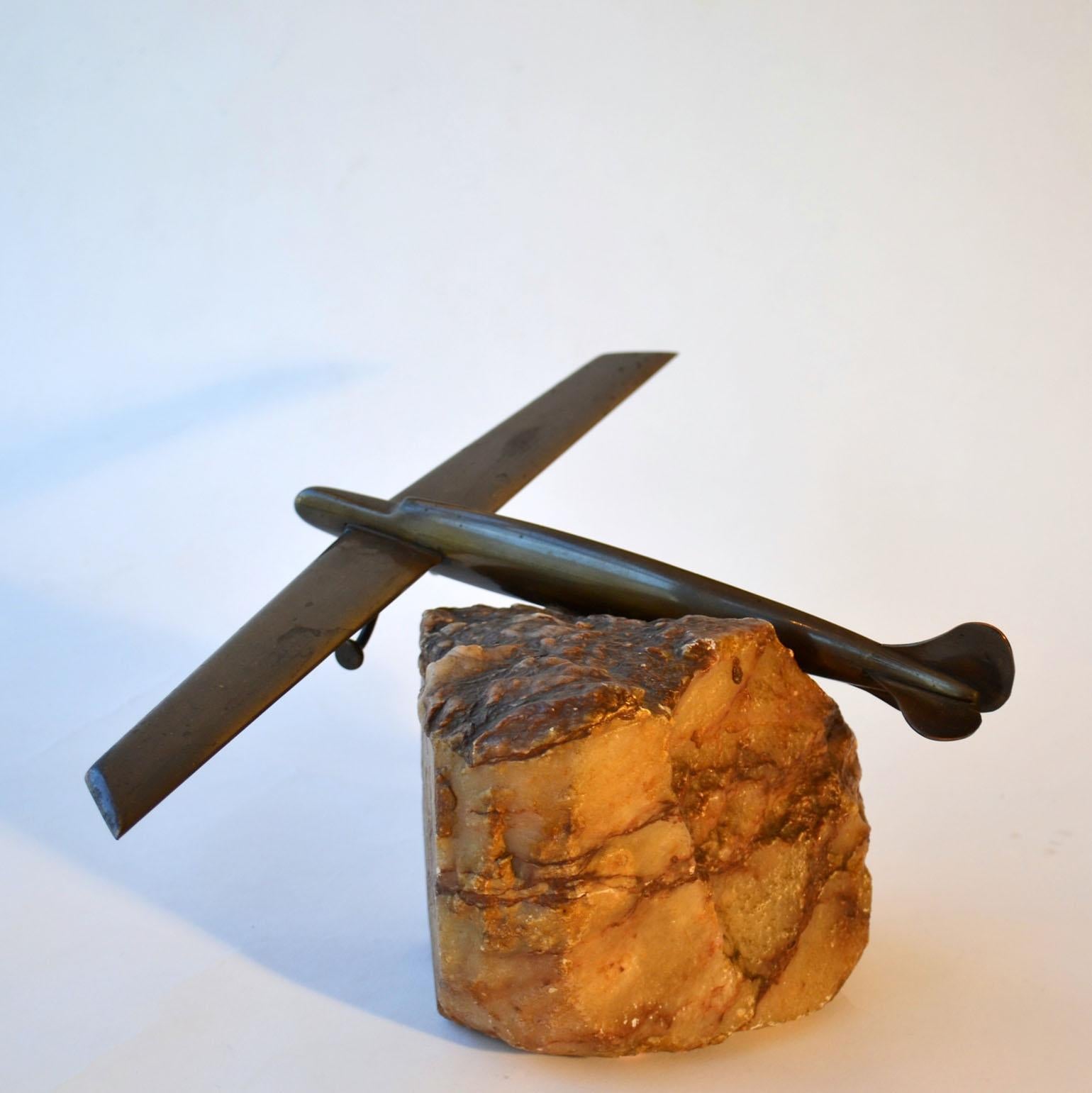 Stylish bronze airplane model, circa 1940s-1950s placed on onyx rock. Decorative sculpture that displays well cupboard, credenza or a desk.