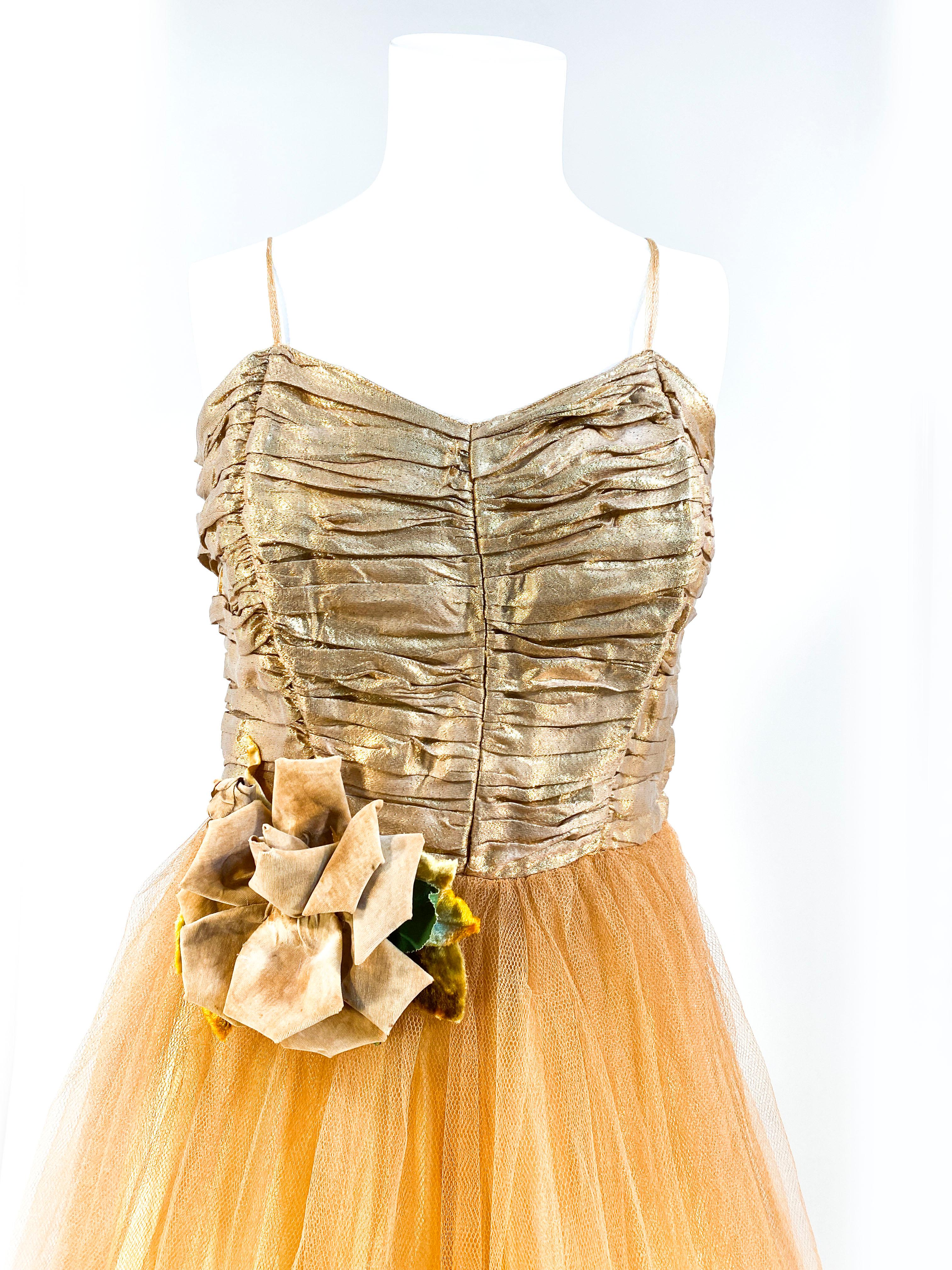 1950s tea-length party dress with gold metallic lamé ruched bodice. The skirt is made of gold layered tulle that is finished with a handmade gold enlarged rose with buds and leaves. The dress is entirely lined with boning in the bodice for