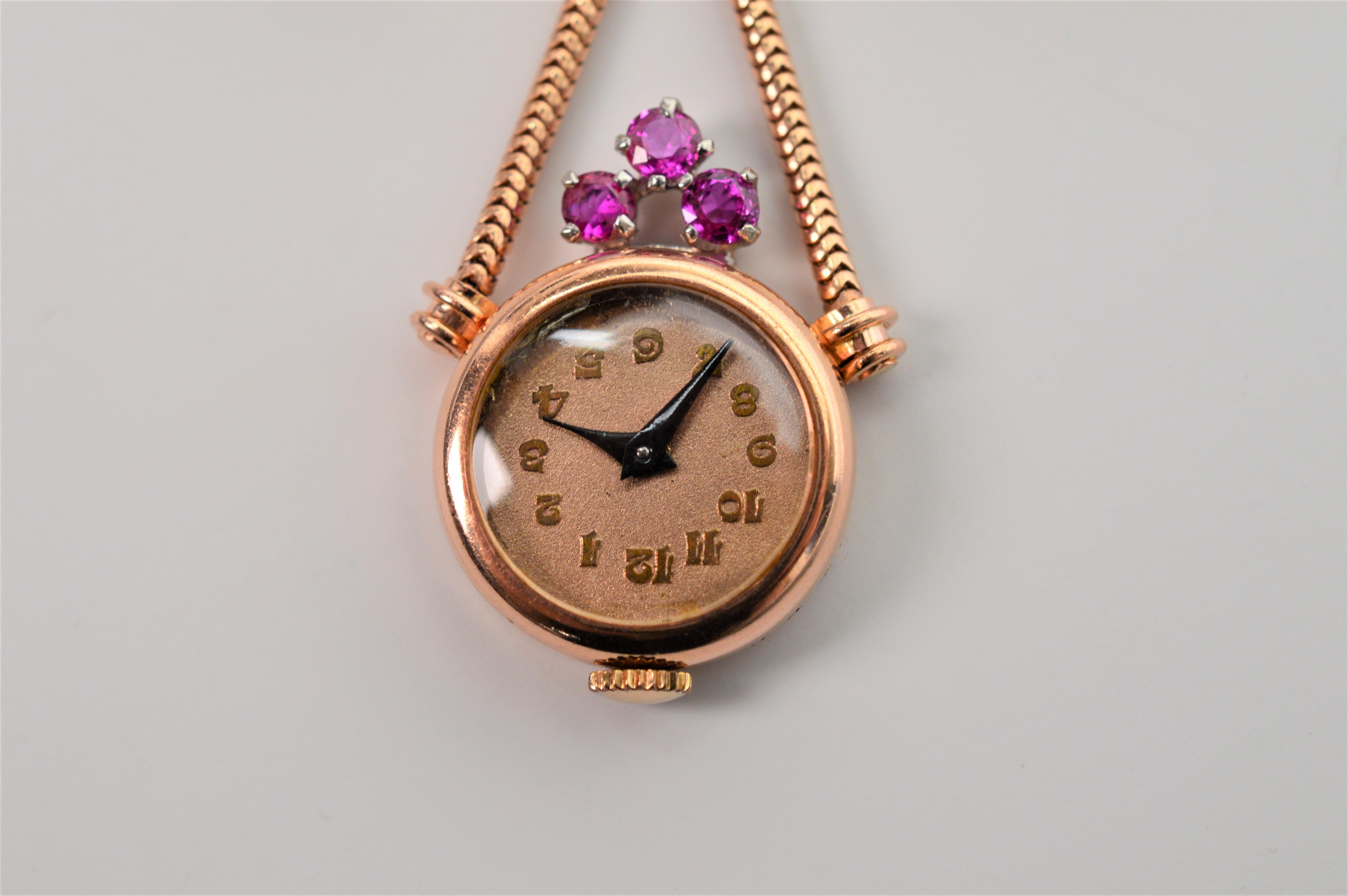 Adorable and an unusual example right out of the 1950's, this 14 Karat Rose and Yellow Gold Pendant Watch Brooch with Ruby Accents is in mint condition. A sweeping rose and yellow gold bow enhanced with European cut diamonds and fine rubies measures