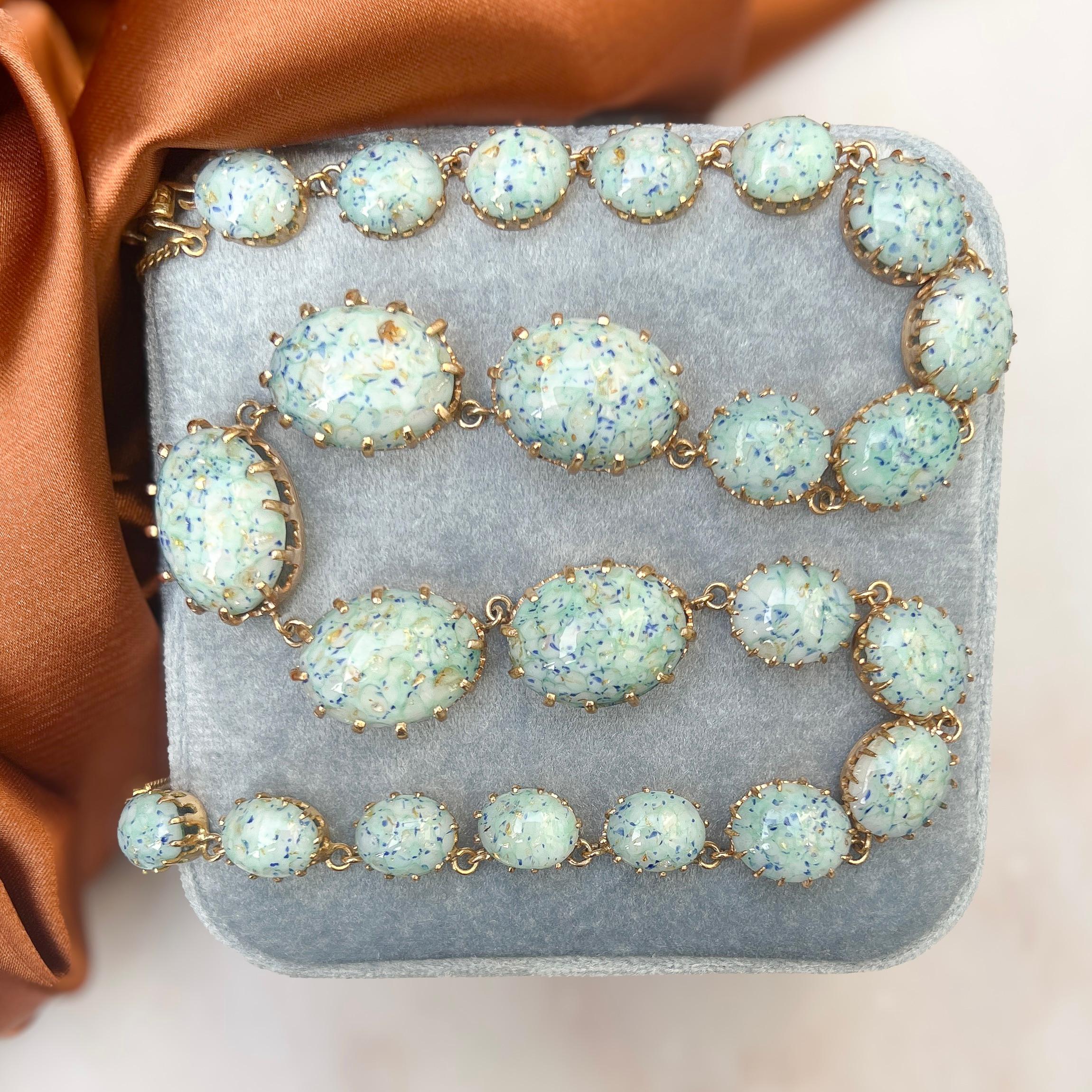 This necklace exudes beautiful quality and design. It was created in the 1950s.

Condition Report:
Excellent

The Details...
This gold plated necklace is detailed with oval cut, speckled glass cabochons along its length, increasing in size with the
