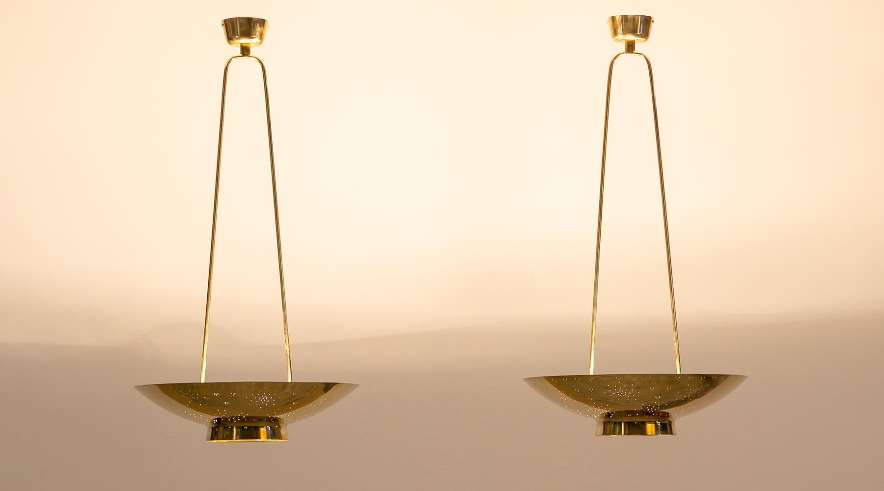 Pair of pendant lamps, brass, Paavo Tynell, Finland, 1955.

Fantastic set of ceiling lamps by Finland classic Paavo Tynell. His cautious hand in light design comes to full effect through this elegant yet unobtrusive set of ceiling lamp with