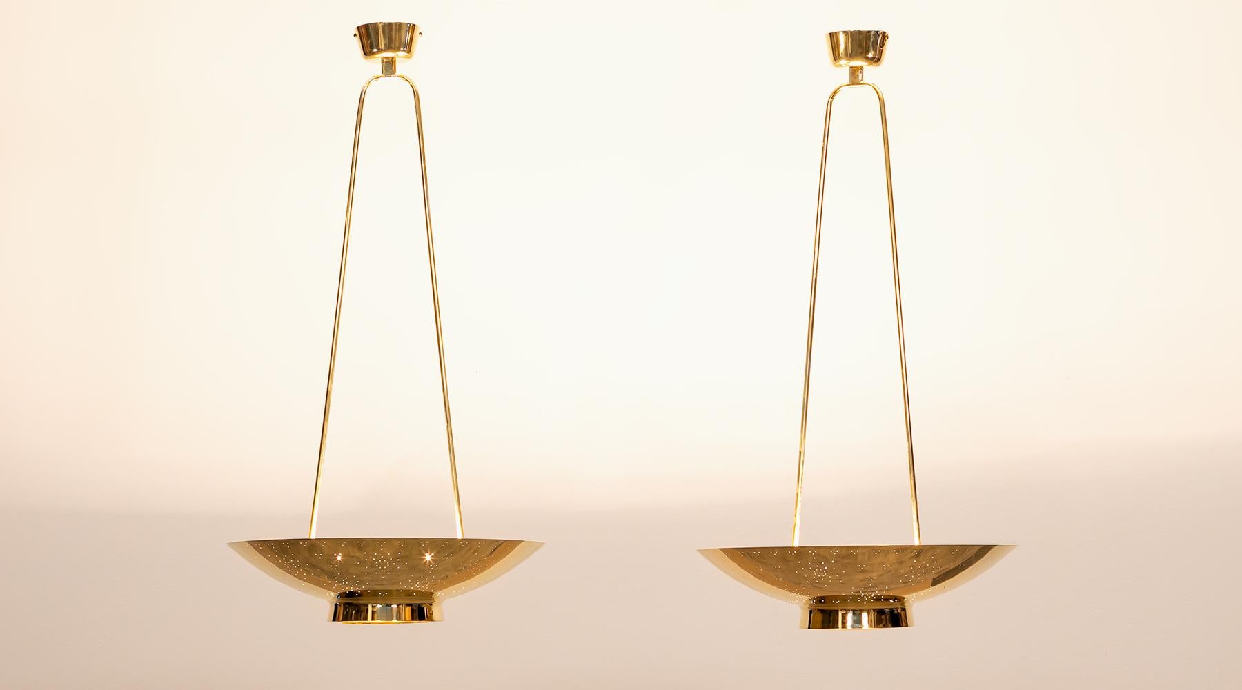 Pair of pendant lamps, brass, Paavo Tynell, Finland, 1955.

Fantastic set of ceiling lamps by Finland classic Paavo Tynell. His cautious hand in light design comes to full effect through this elegant yet unobtrusive set of ceiling lamp with