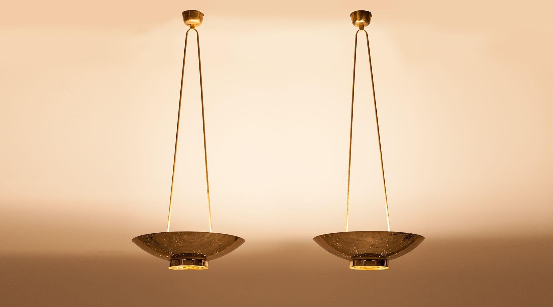 This very elegant pair of ceiling lamps are made of highest quality by famous Finish Paavo Tynell. The solid perforated brass pendant with etched glass downlight lives trough its simple, understated pure form. 
Manufactured by Taito Oy. 

Paavo