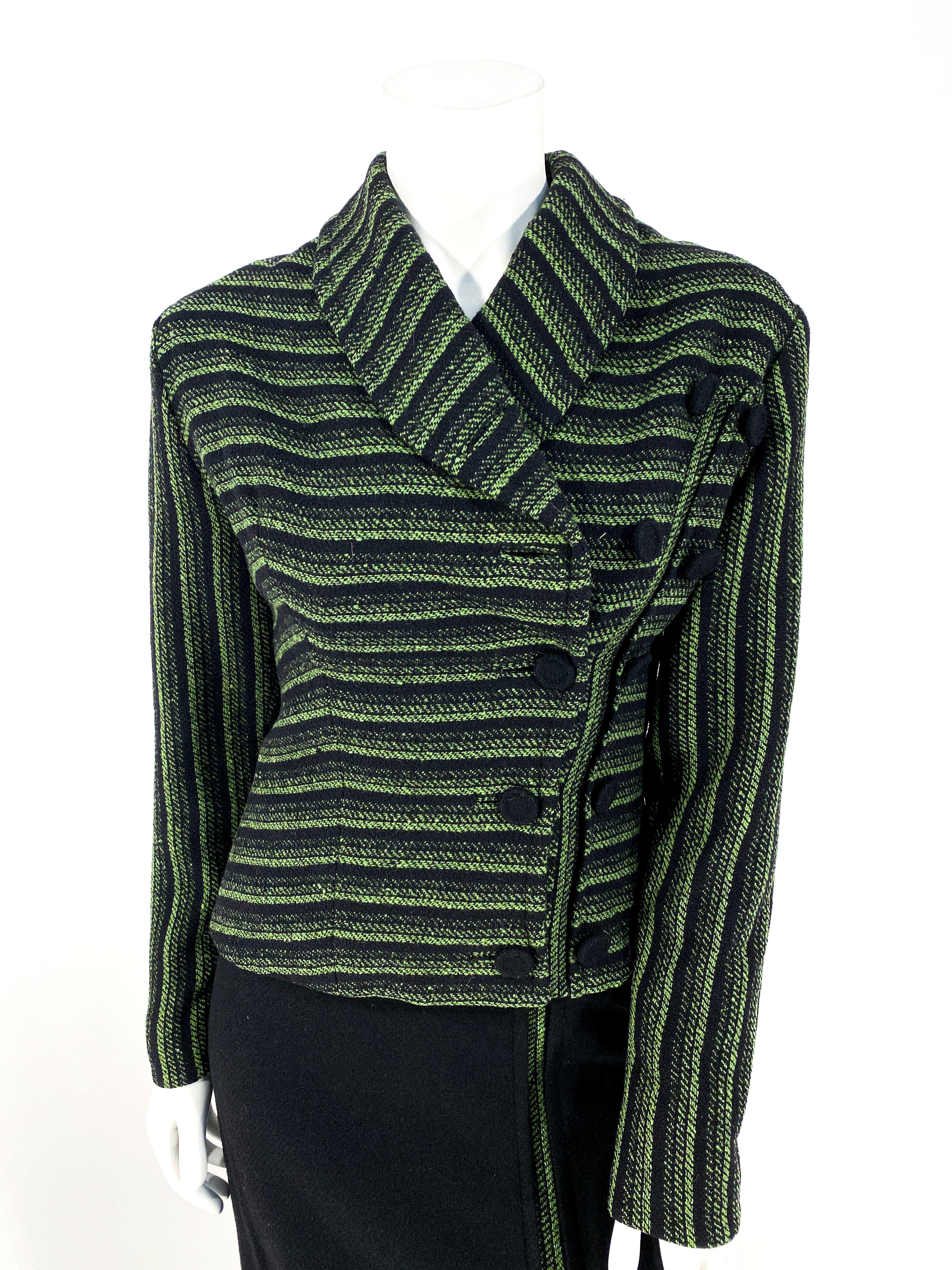 1950s wool suit featuring shades of olive, sage, and forest green with an asymmetrical button closure accented with additional matching hand-covered buttons. The shawl collar is modified to accommodate the asymmetrical closure. The black wool has a
