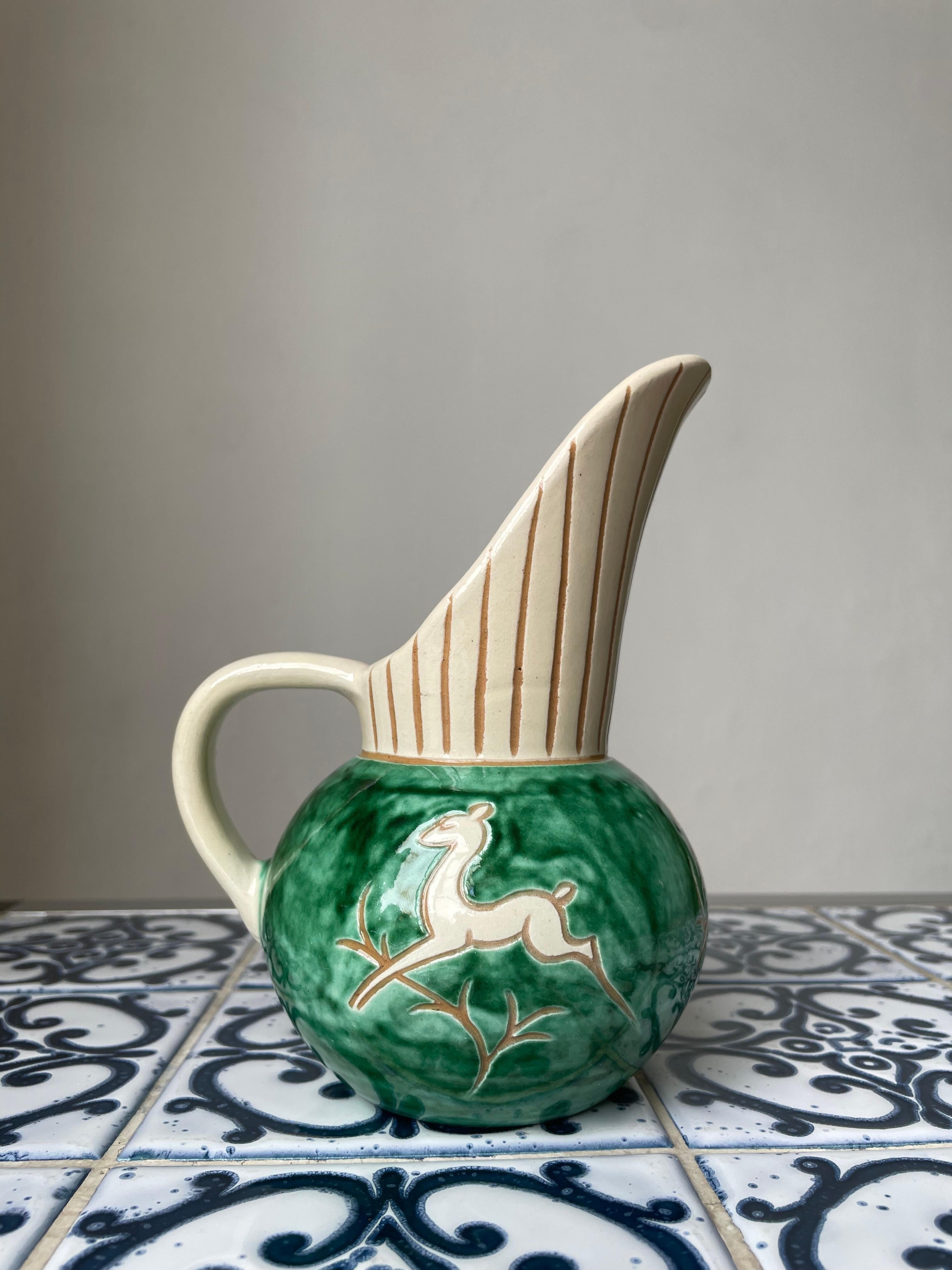 Handmade and hand-painted Danish midcentury modern ceramic pitcher vase from the 1950s. Incised lines on neck and organic jumping deer motifs on body. Green and cream colored glaze. Manufactured by Haunsø Ceramics.