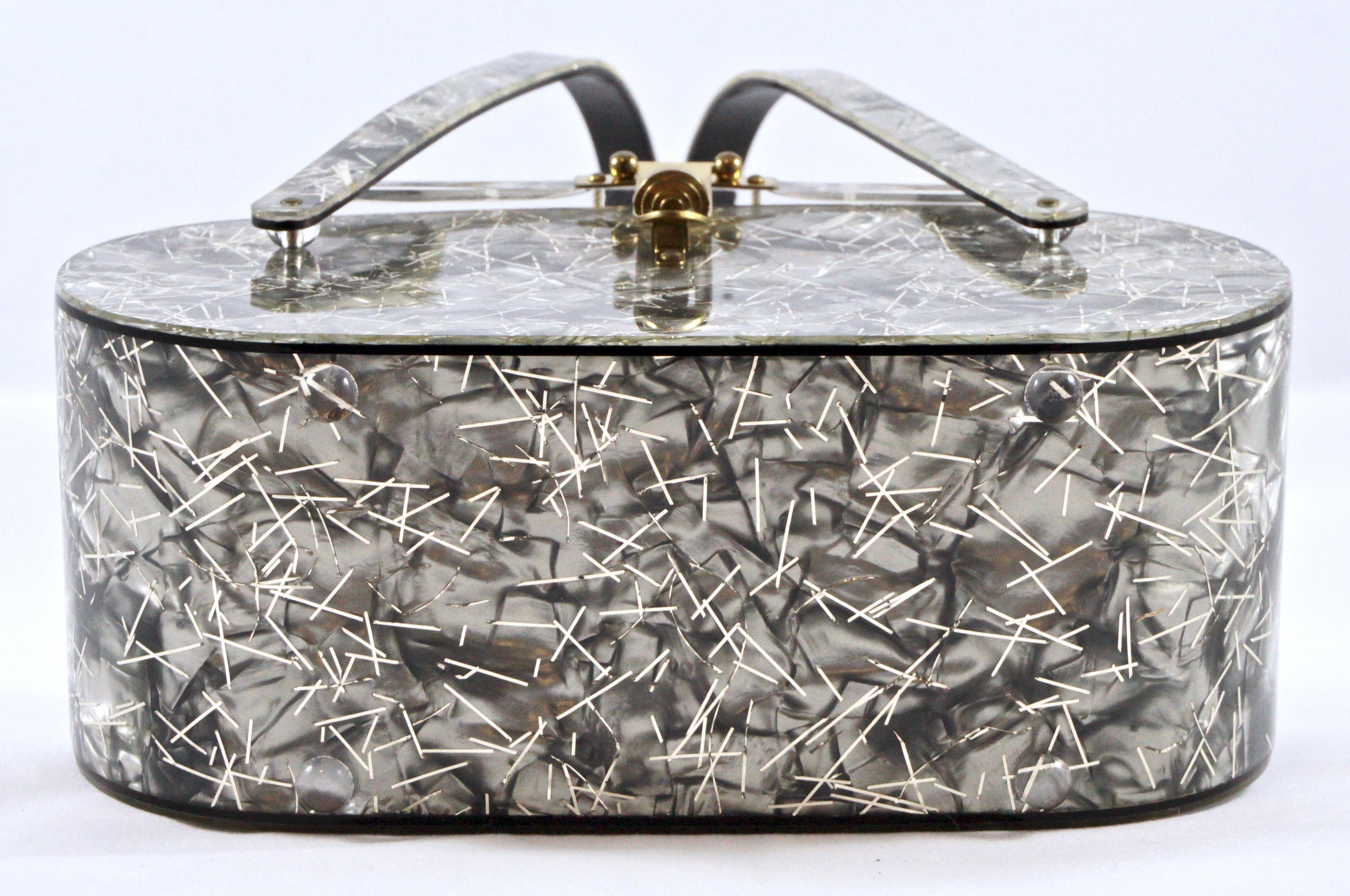 Fabulous marbled grey lucite handbag embedded with strands of silver confetti, and featuring a lovely white flower design carved on the clear lid. Inside the bag has a high gloss black finish, which also lines the handles and edges the bag. There is